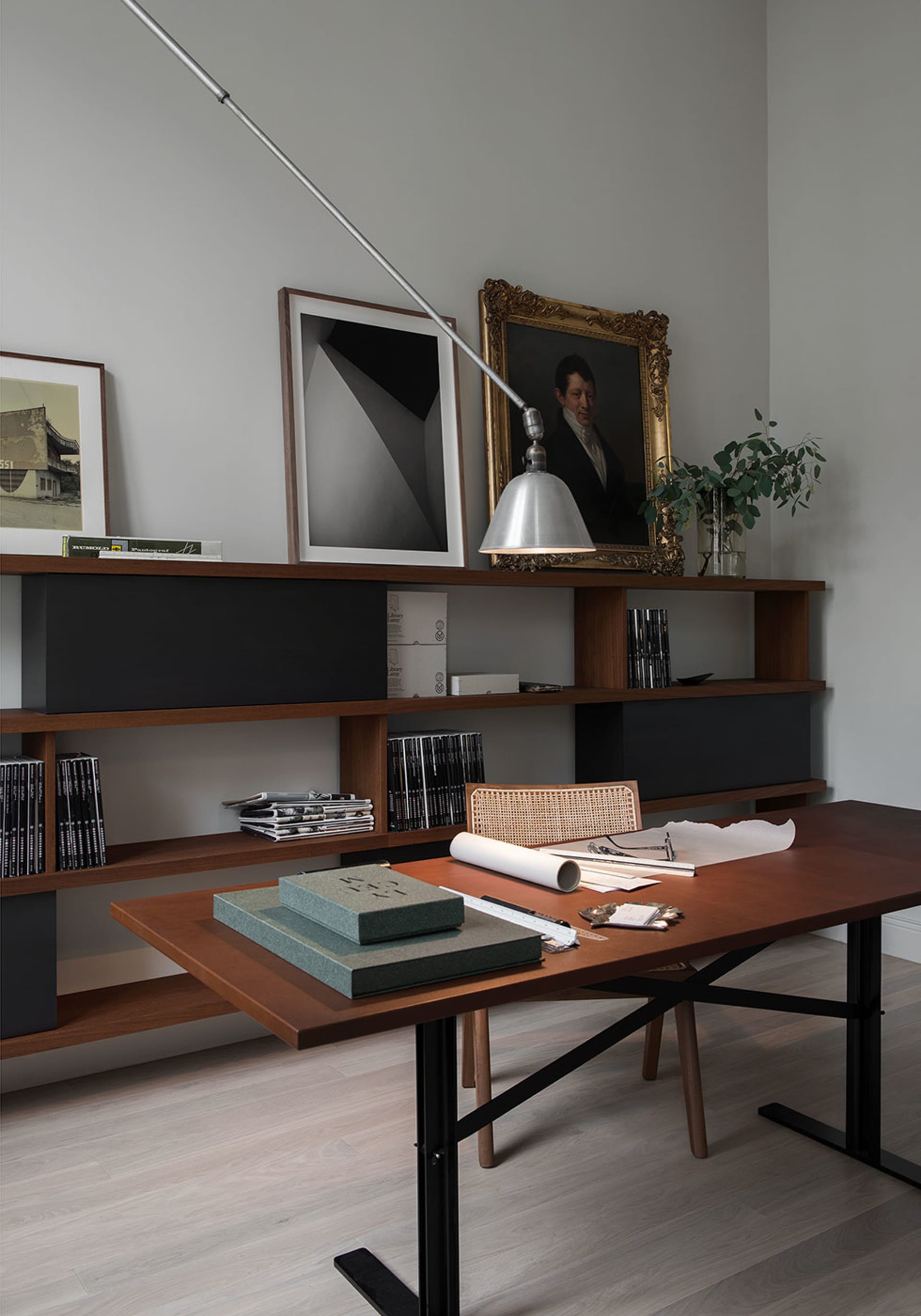 A modern office workspace featuring a wooden desk, shelves, and lighting.