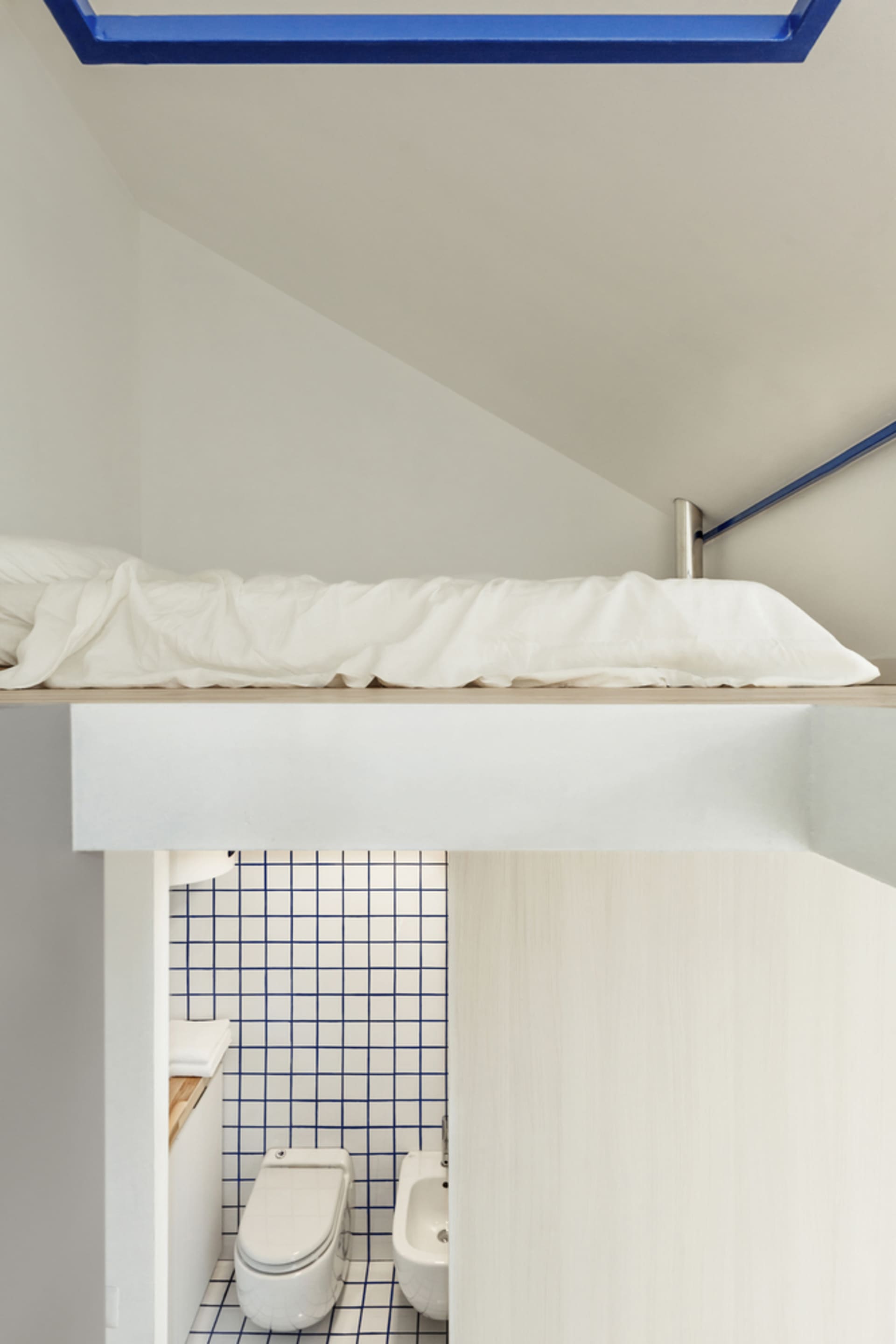 A minimalist bedroom with blue and white checked tile walls.