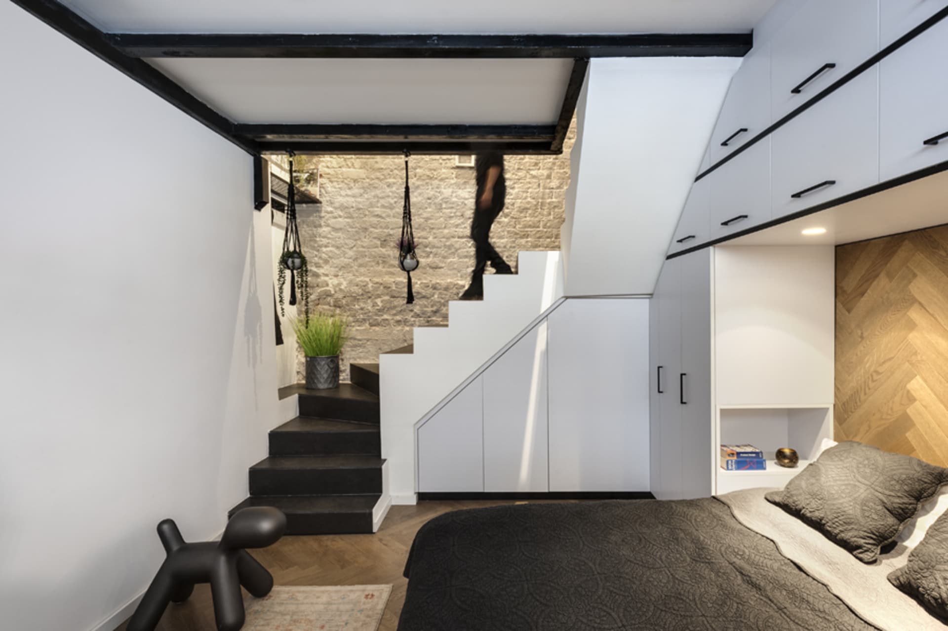 A modern industrial bedroom with concrete stairs, wooden flooring, and minimalist design.