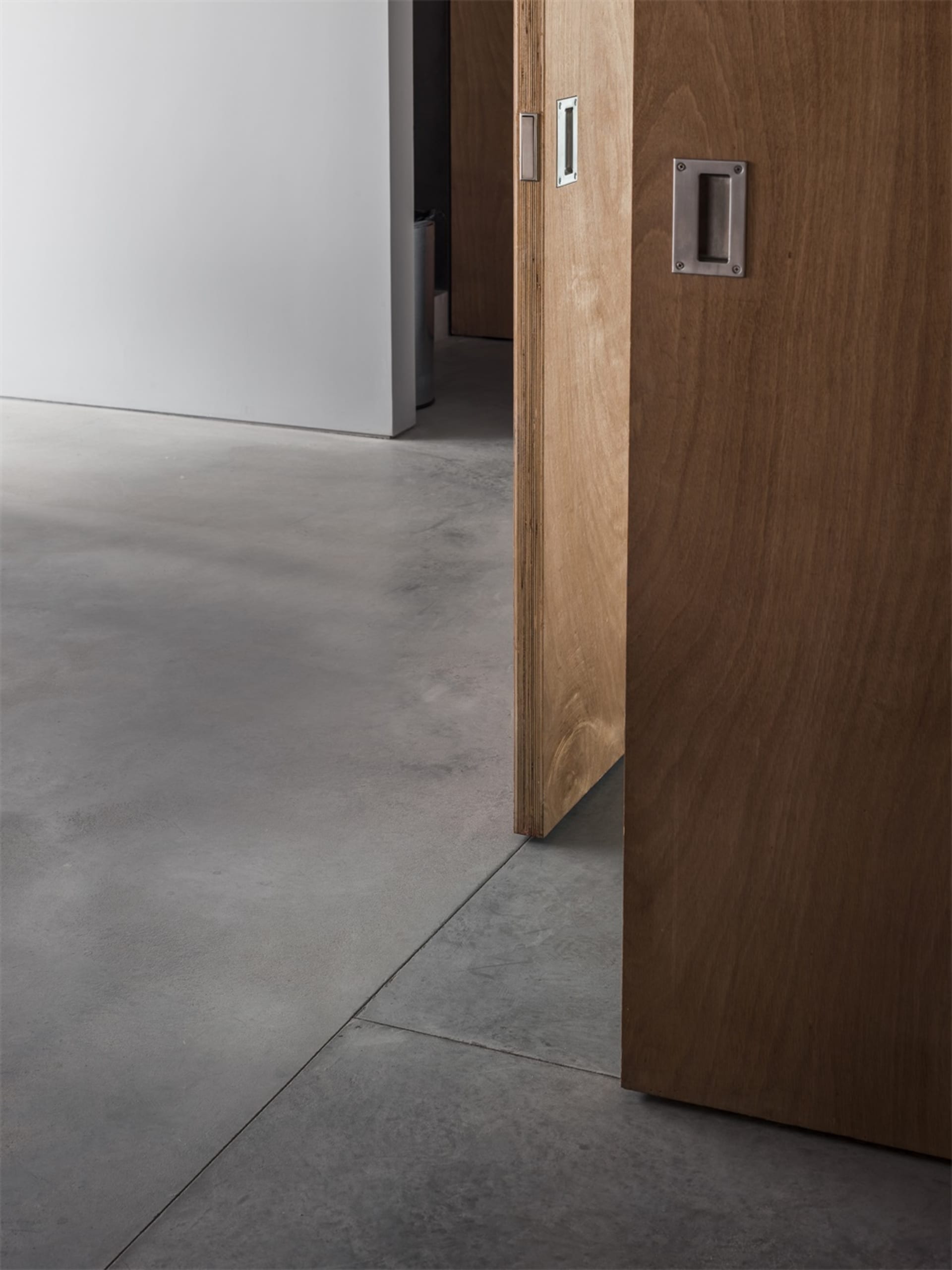 A wooden door with a concrete floor, showing a minimalist and modern aesthetic.