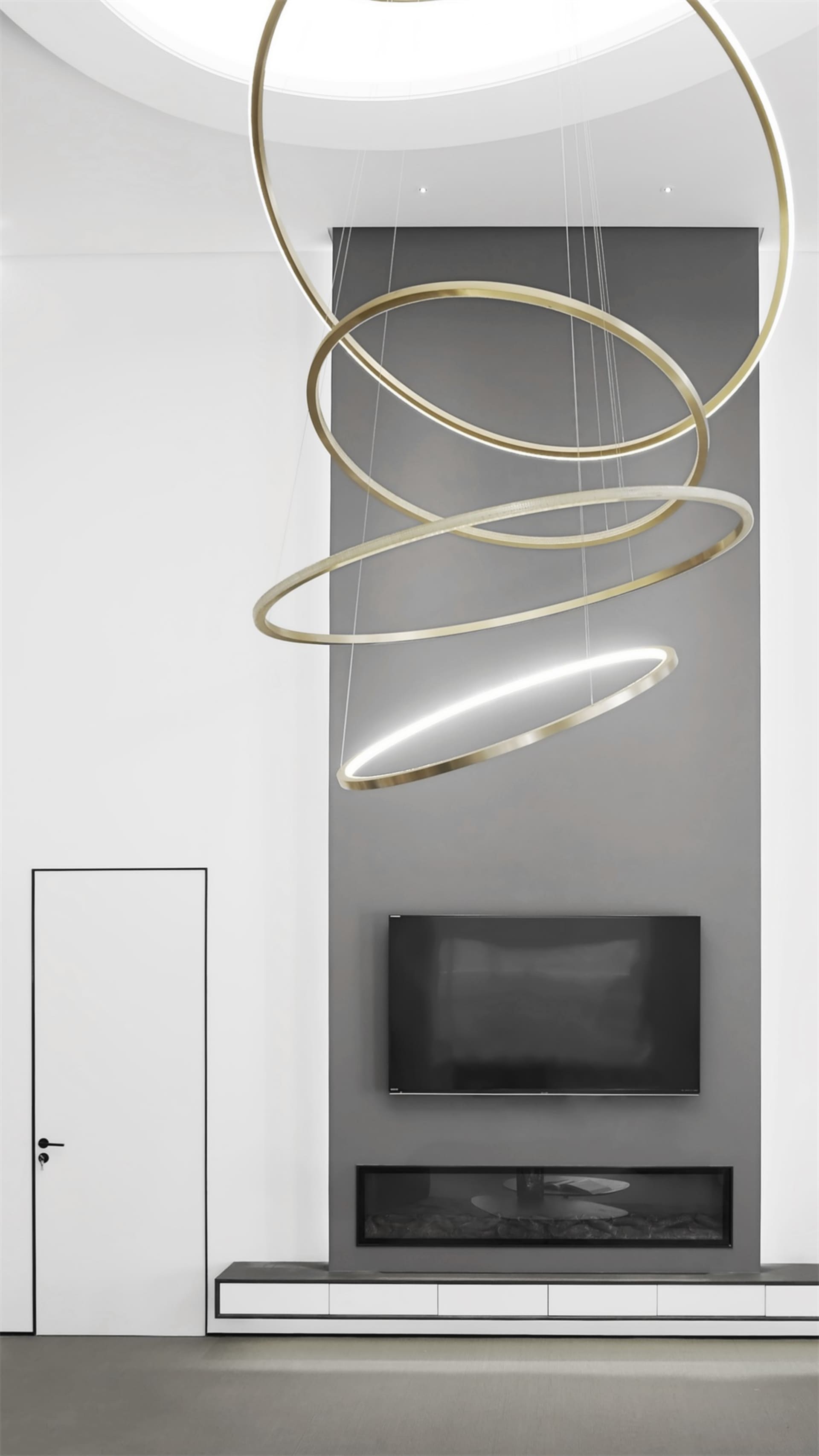 A minimalist living room with modern metallic lighting fixtures, stone flooring, and a glass fireplace insert.