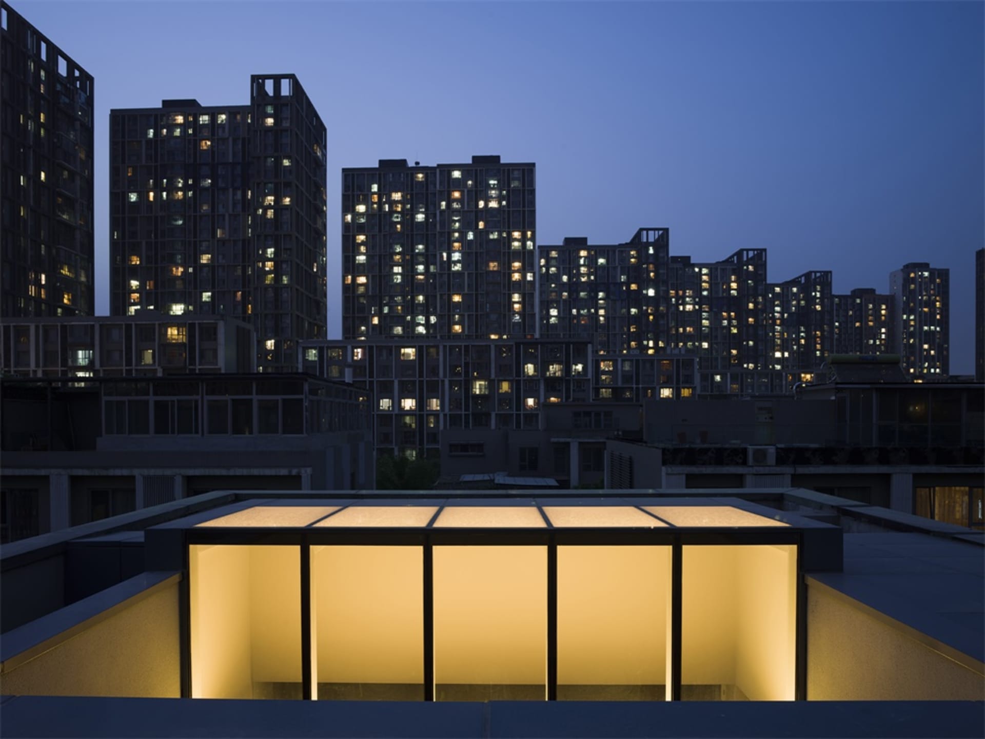 A modern cityscape with illuminated buildings at dusk.