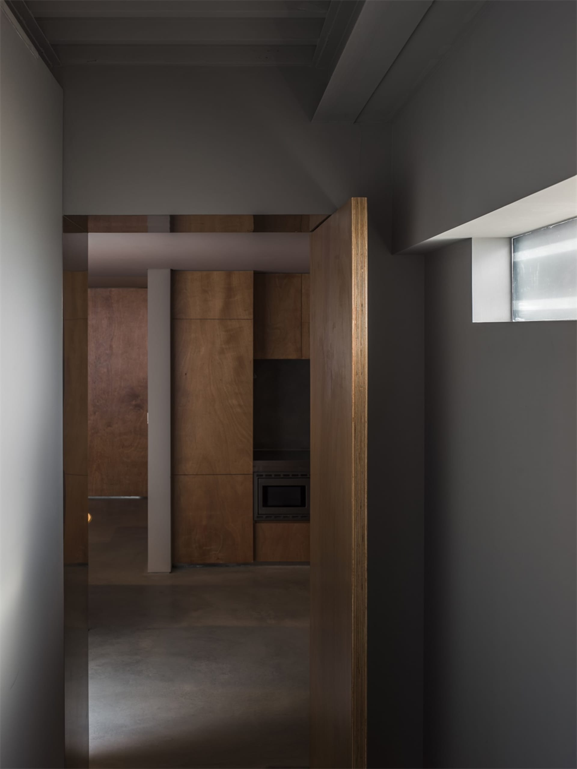 Modern kitchen interior with wooden cabinets and concrete flooring.