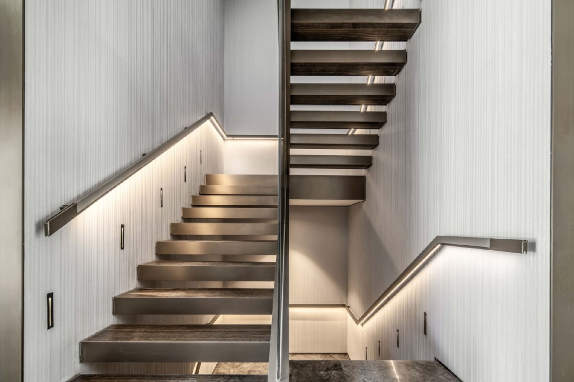 Modern metal staircase with illuminated steps and handrails.