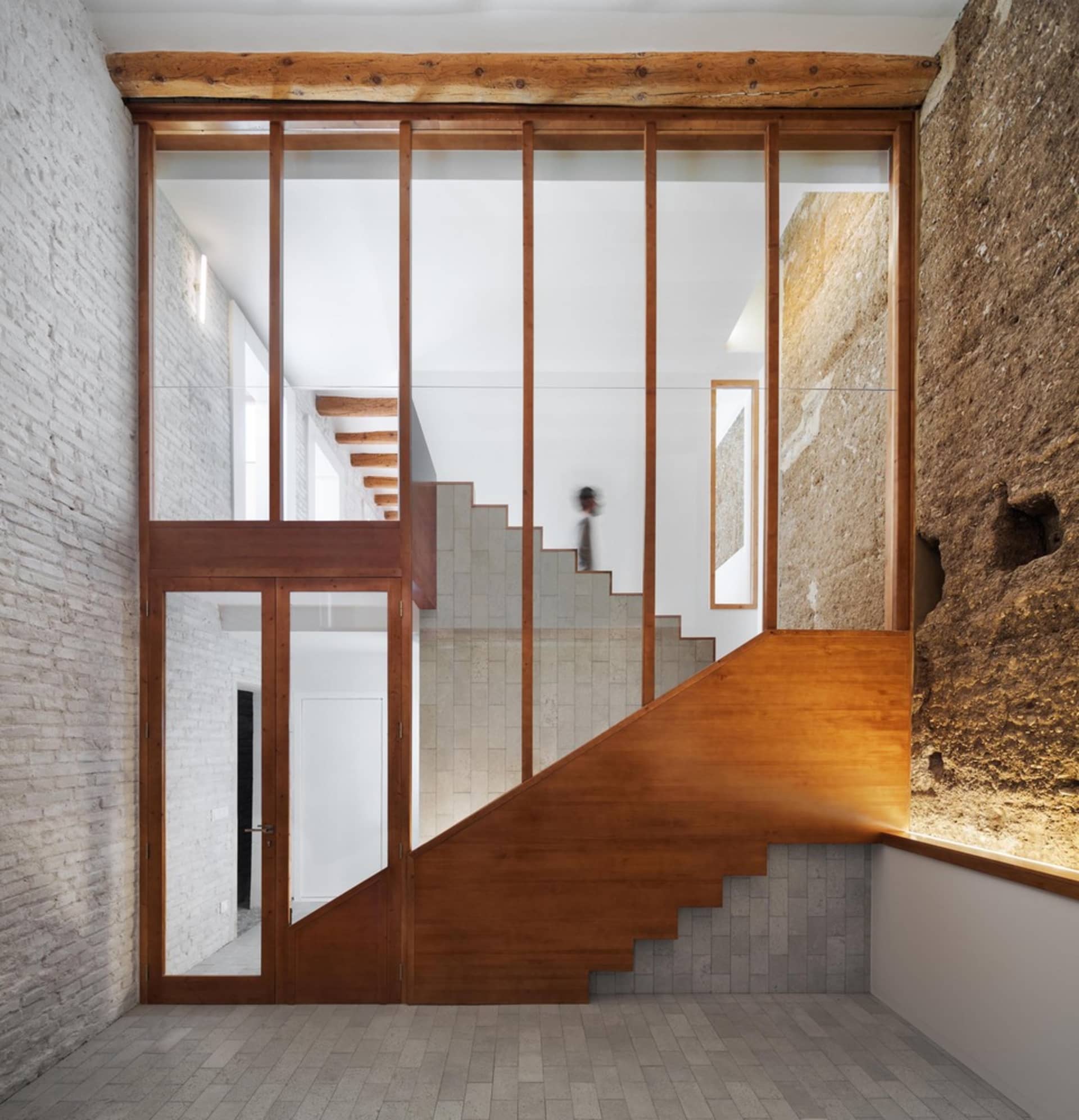 Modern staircase featuring glass panels and brick walls