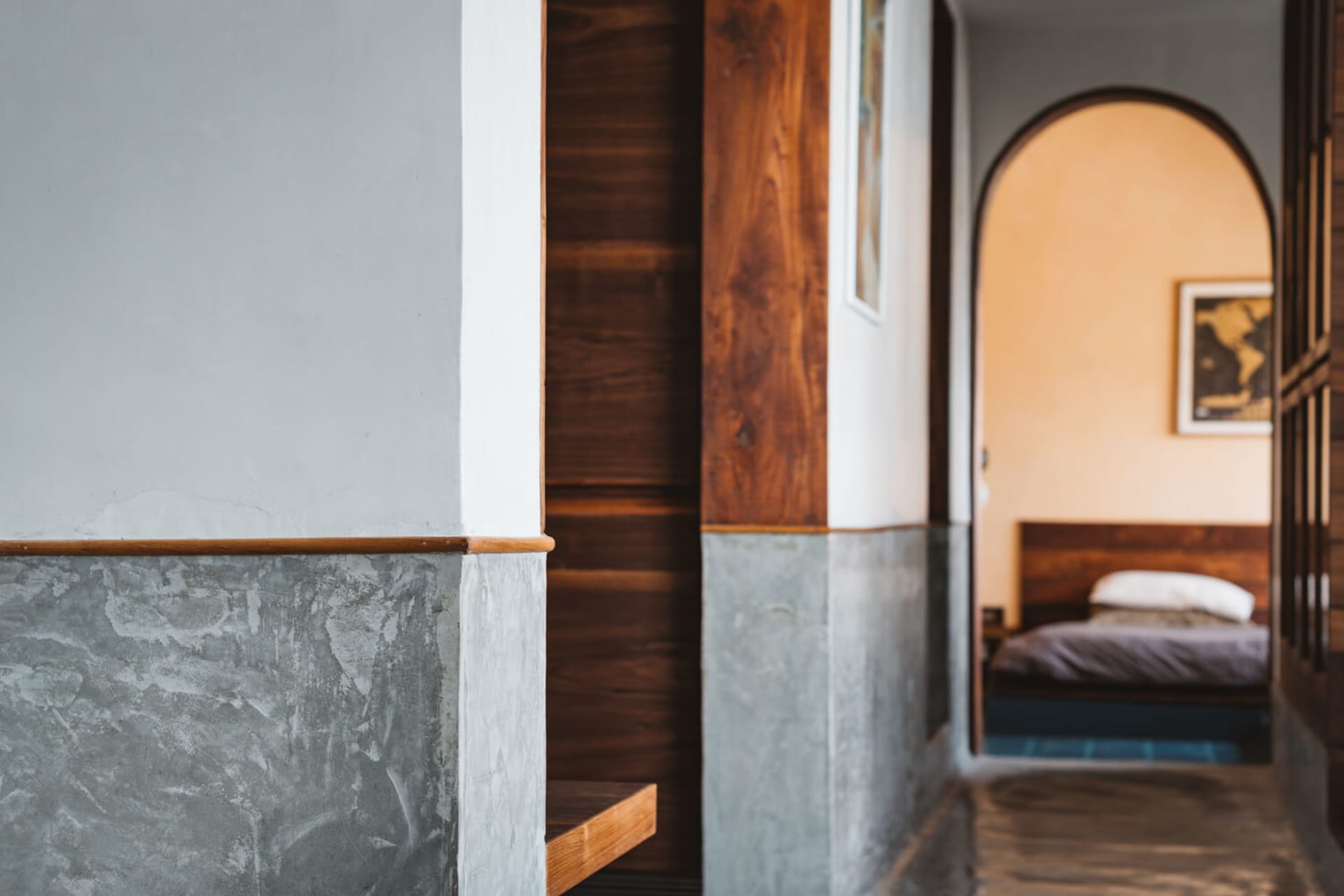 A minimalist bedroom with concrete, wood, and metal elements.