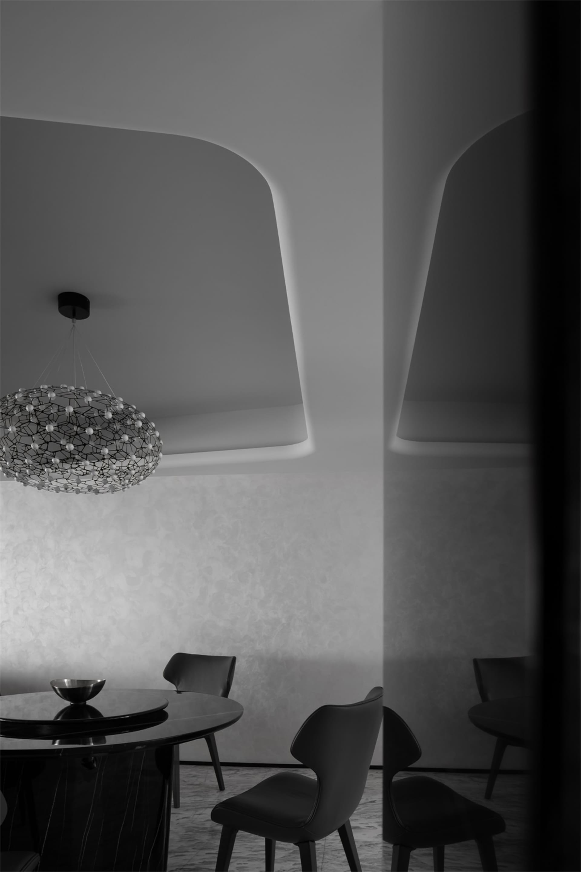 A modern dining room with black and white decor, featuring a round table, chairs, and a geometric chandelier.