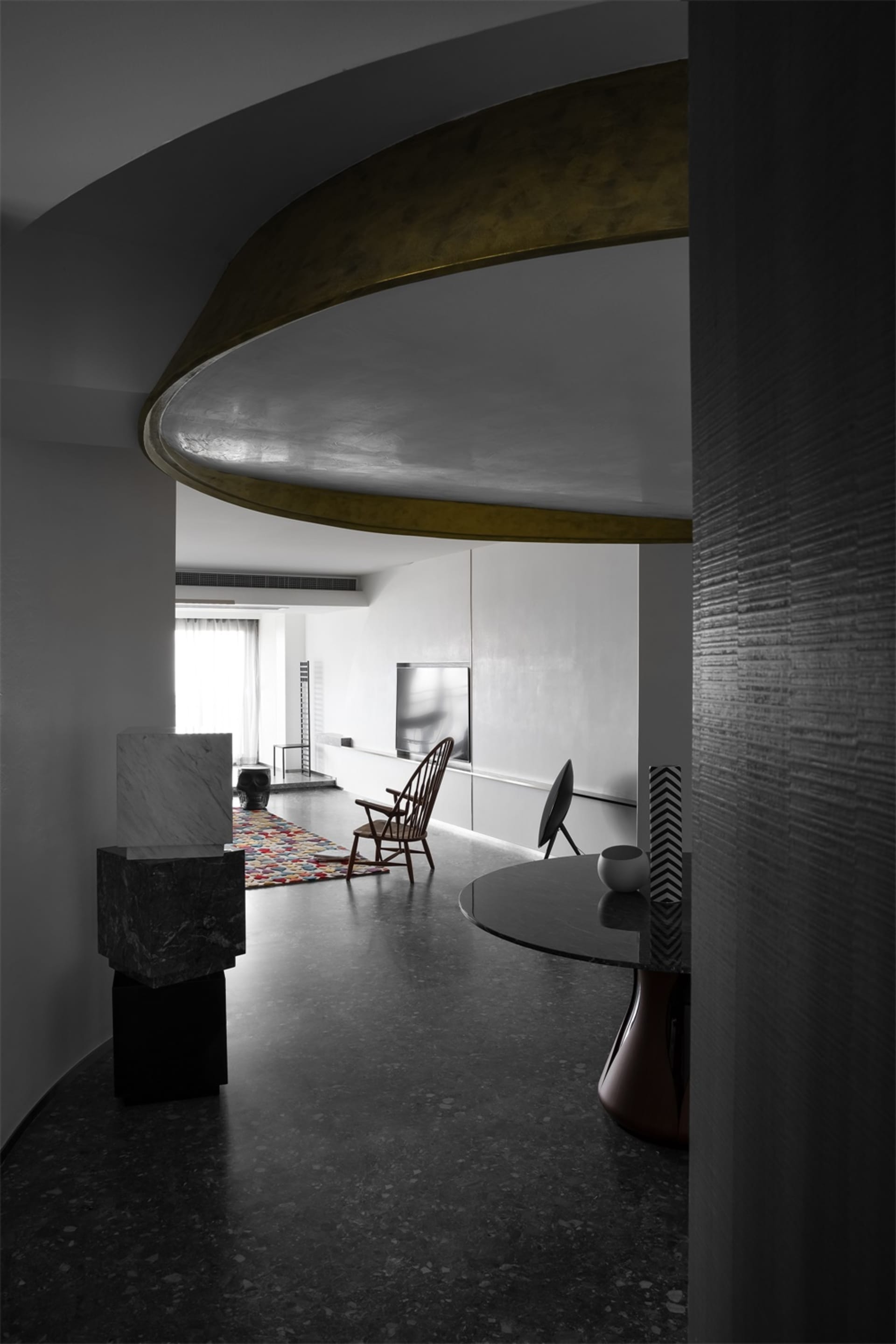 A modern interior featuring concrete elements, minimalist furniture, and a circular architectural design.