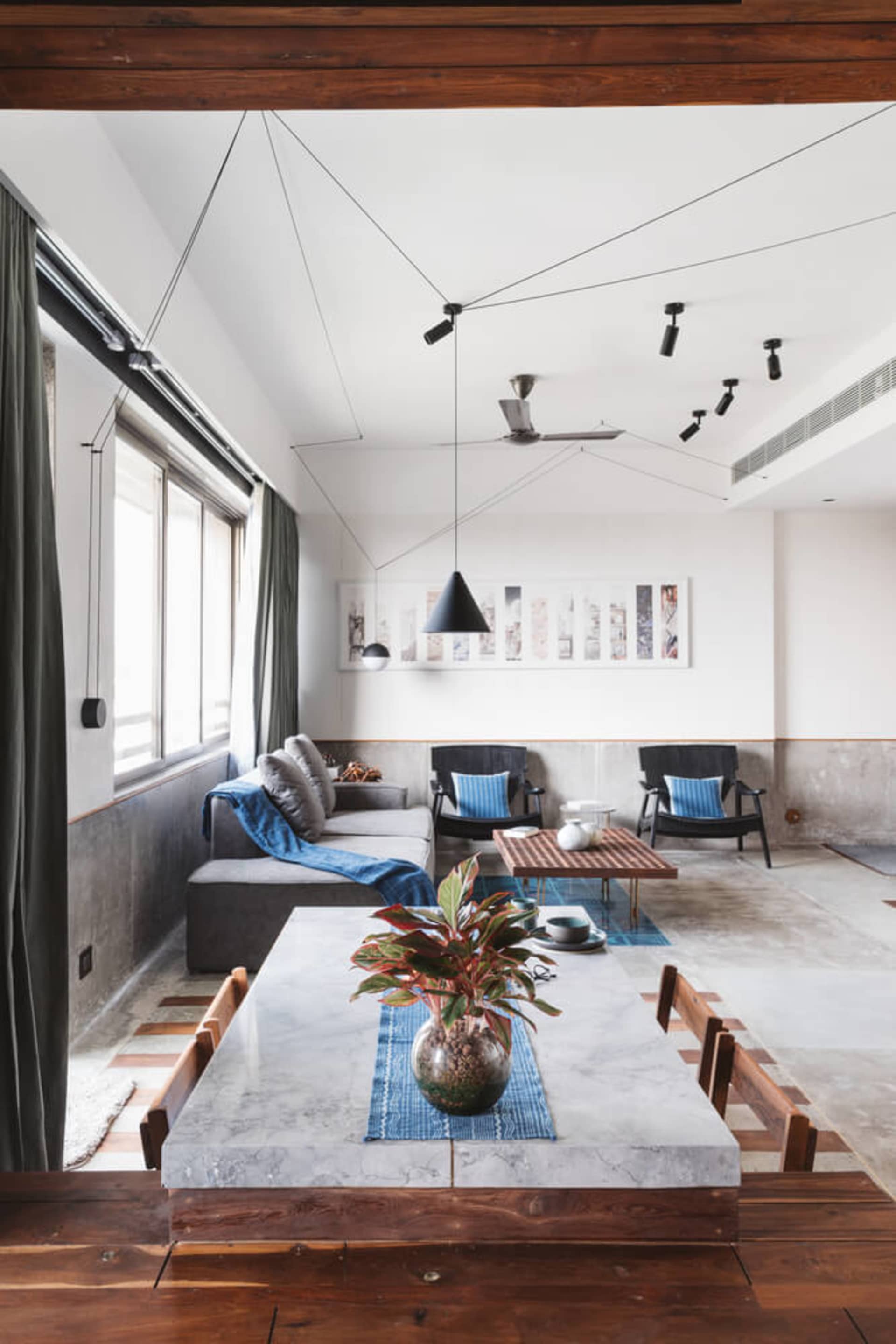 Modern living room featuring concrete, smoked wood, marble, and plants.