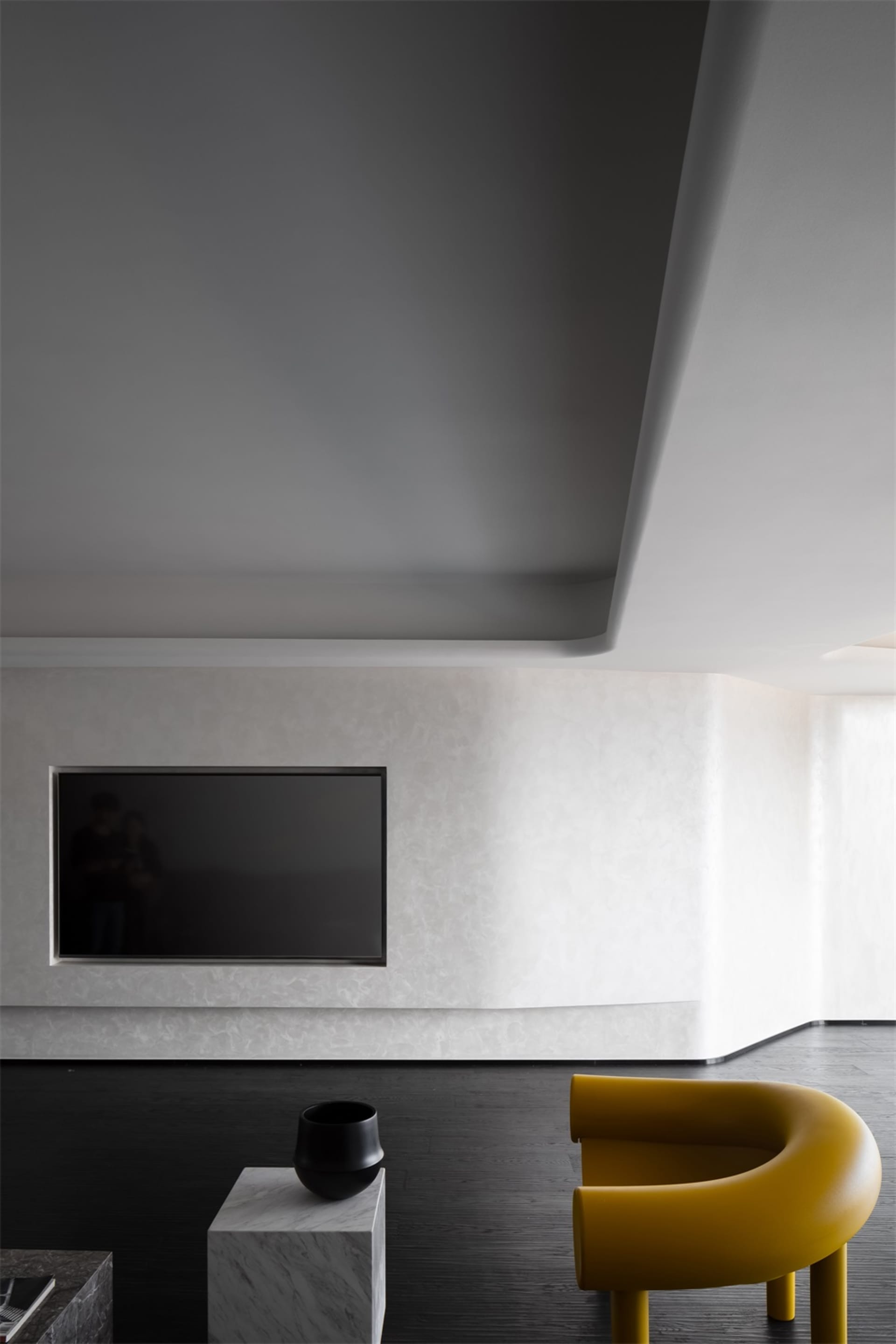 Modern living room featuring minimalist furniture, black and yellow chairs, a marble coffee table, and a flat-screen TV mount