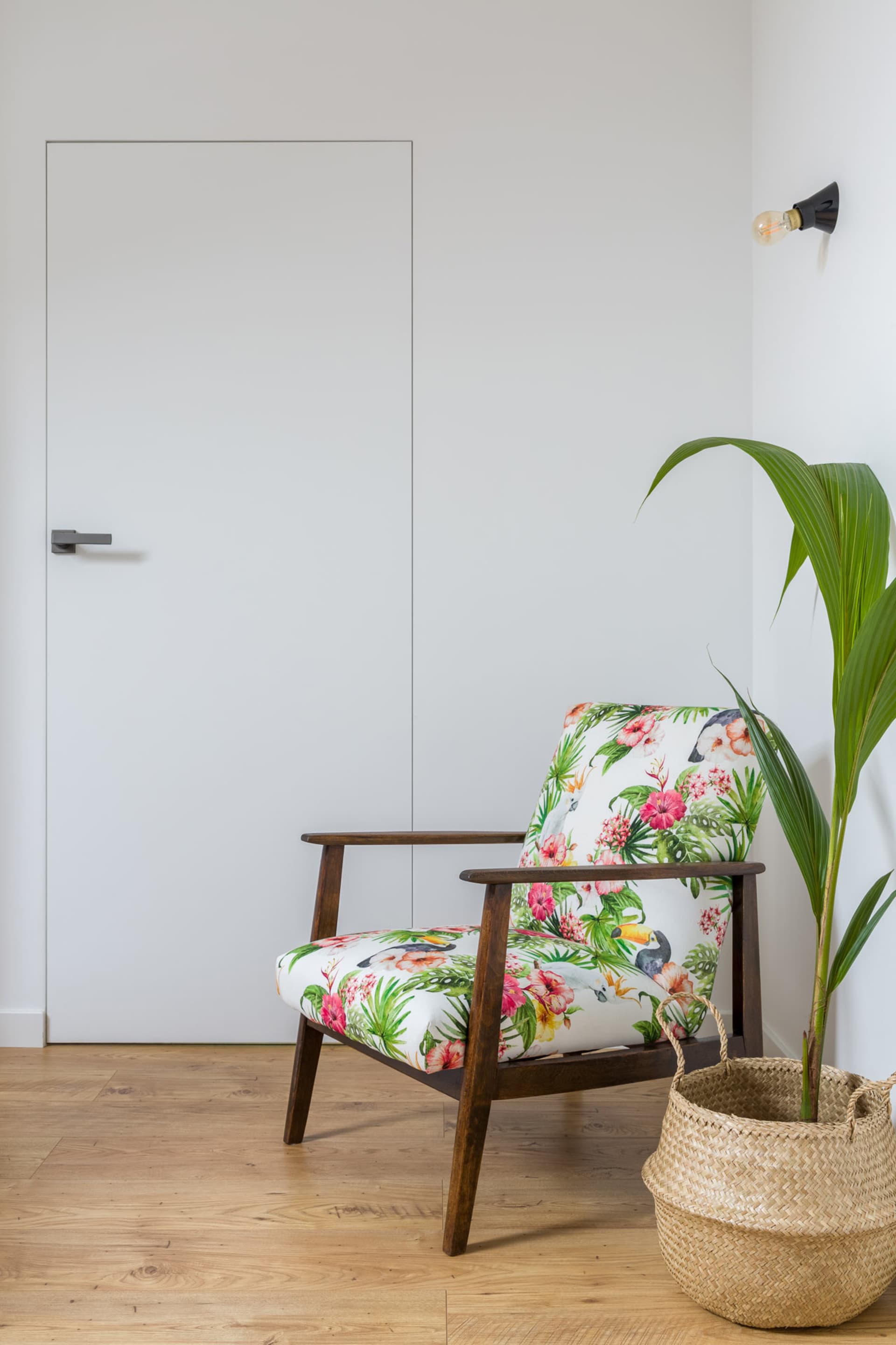 A tropical-themed living room with a wooden armchair featuring a floral and bird design.