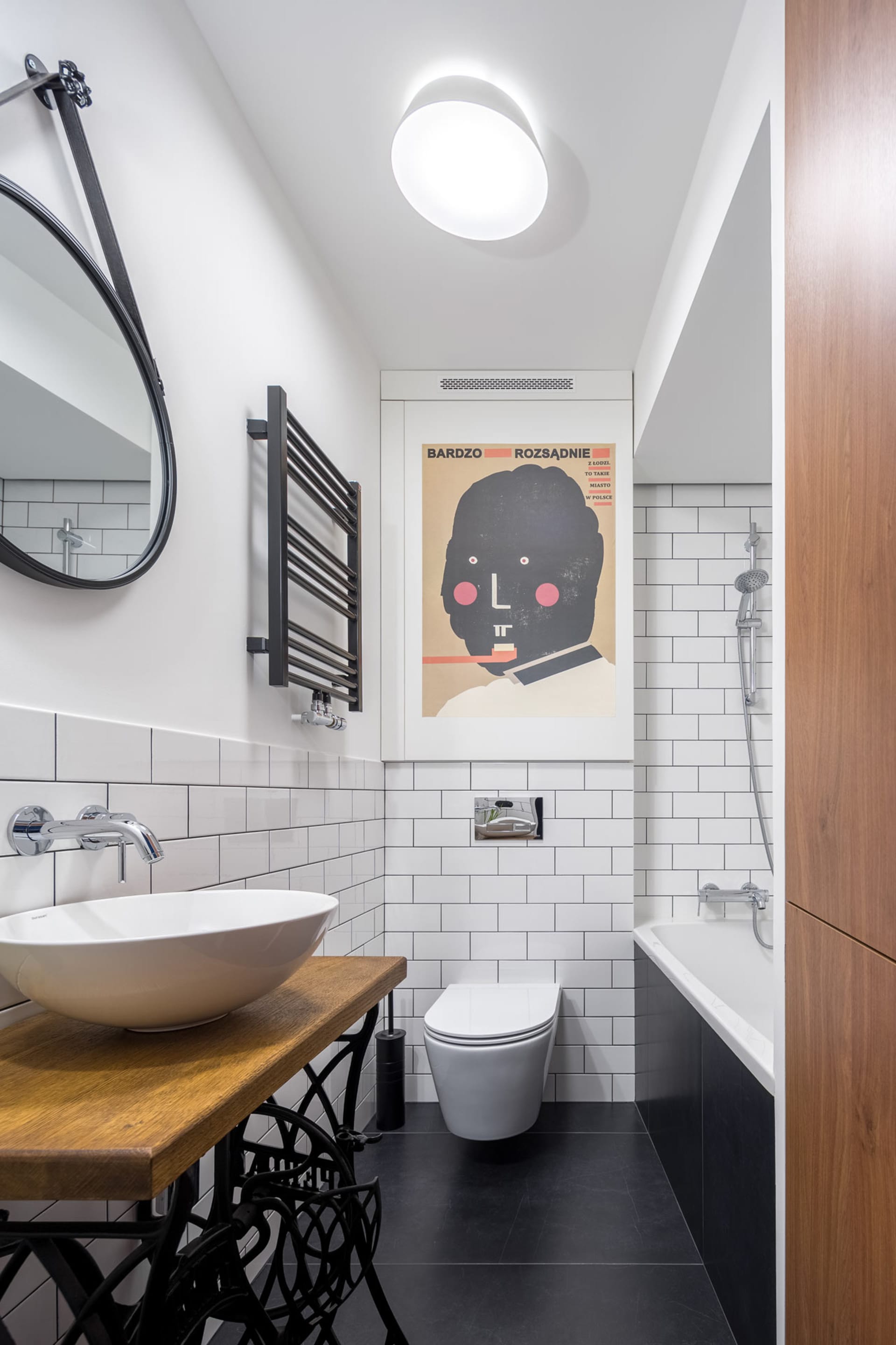 Modern bathroom with white subway tiles, black floor tiles, and minimalist design.