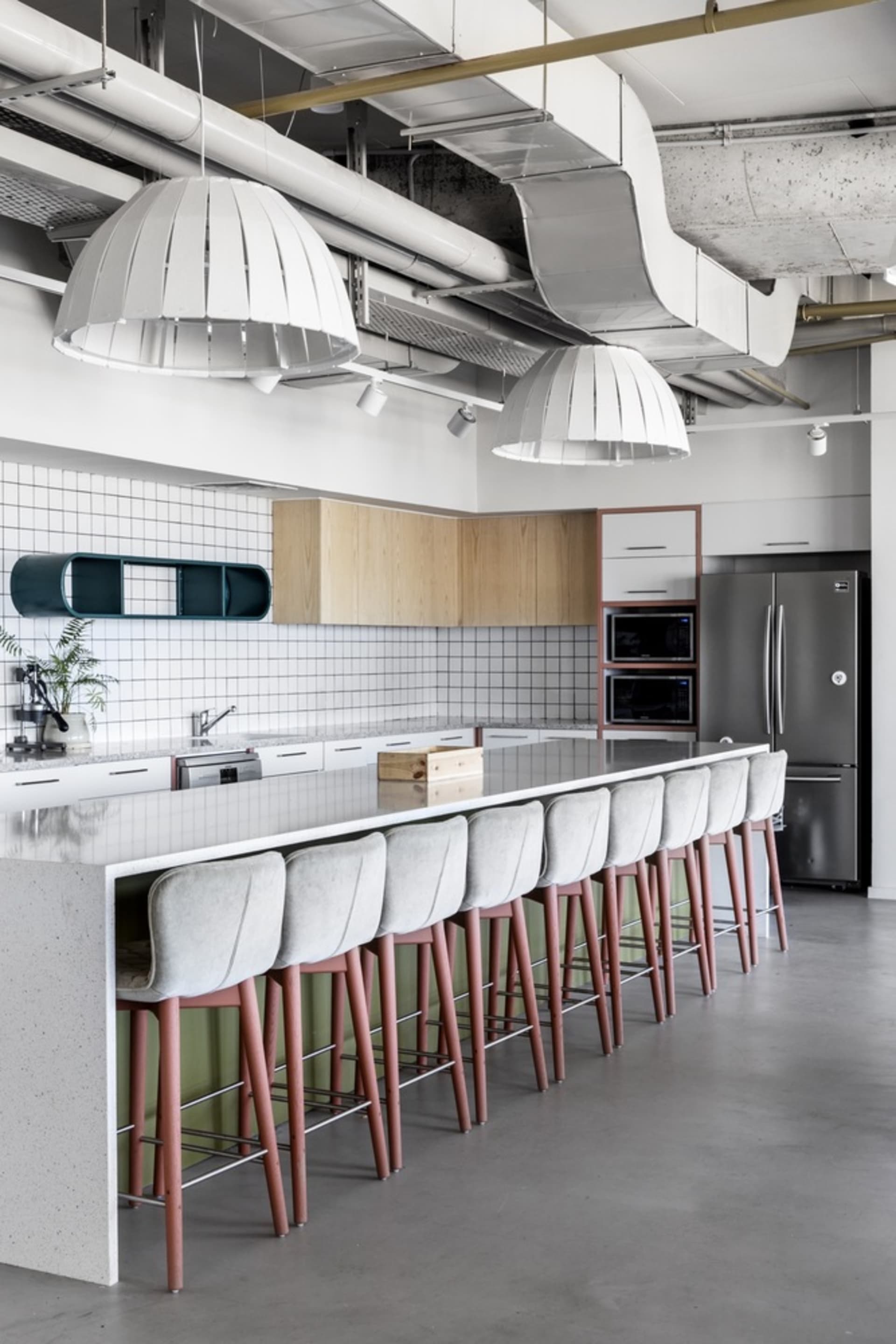Industrial-style modern kitchen with concrete countertops and wood cabinetry.