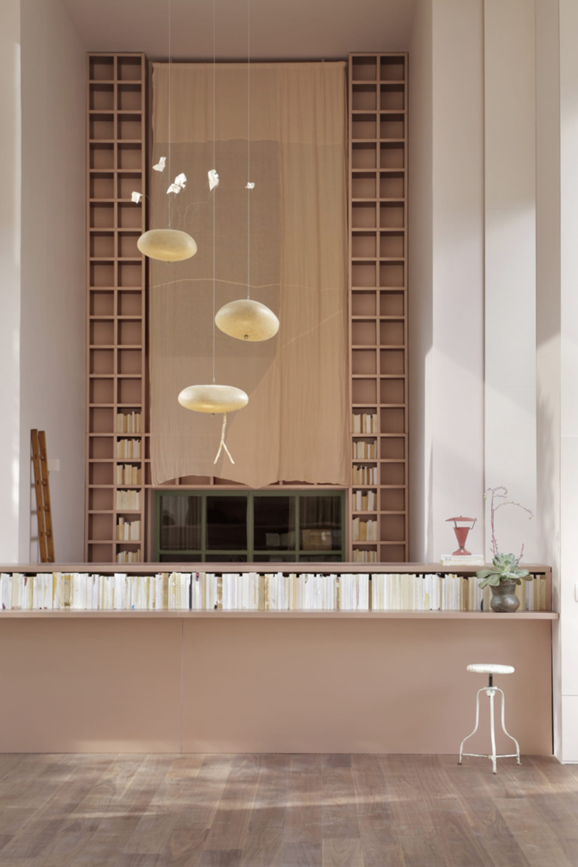 A modern library with glass shelves, wooden reception desk, and metal stools.