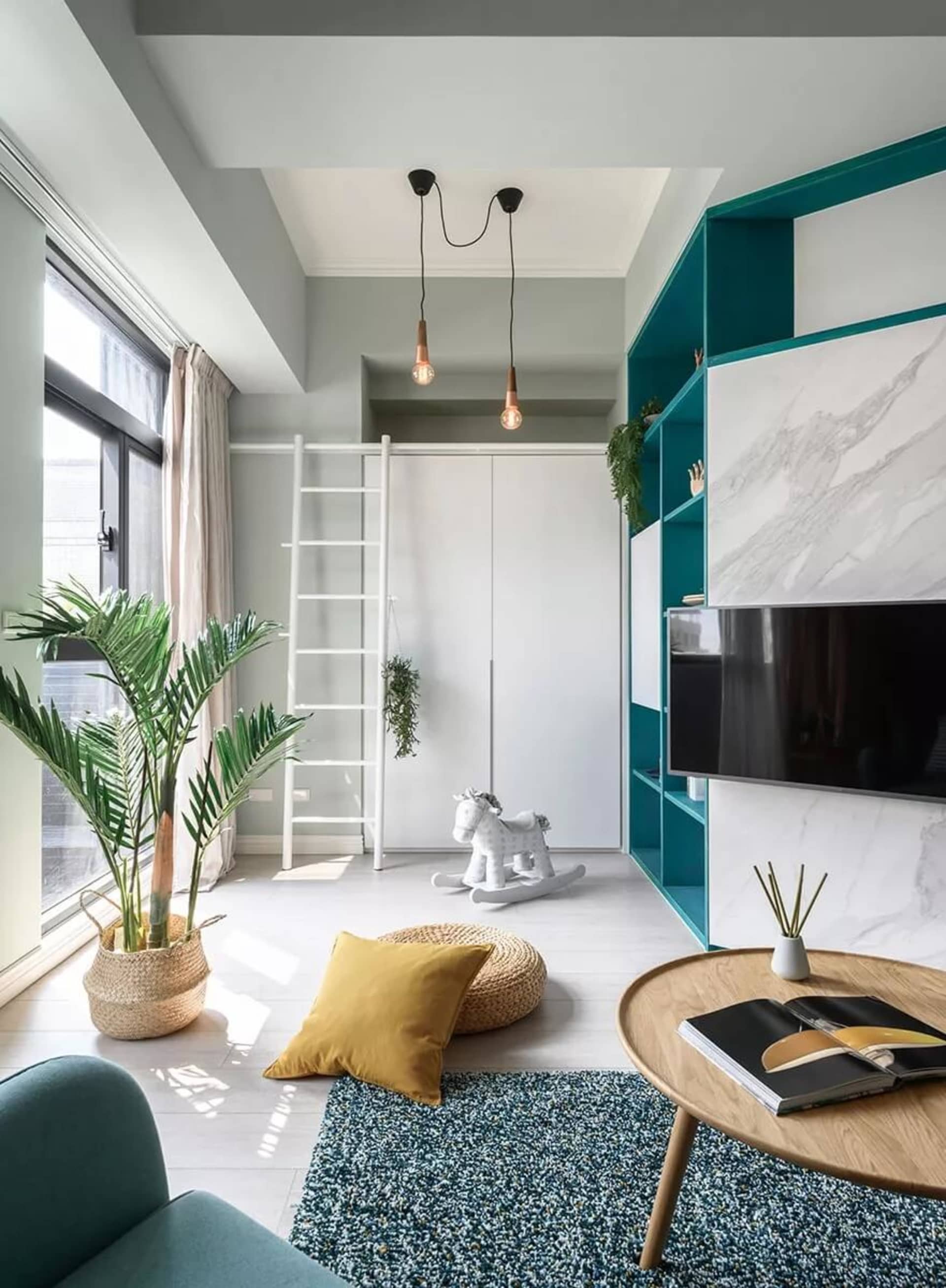 A modern minimalist living room with concrete walls, a turquoise accent wall, and a combination of white, turquoise, and teal