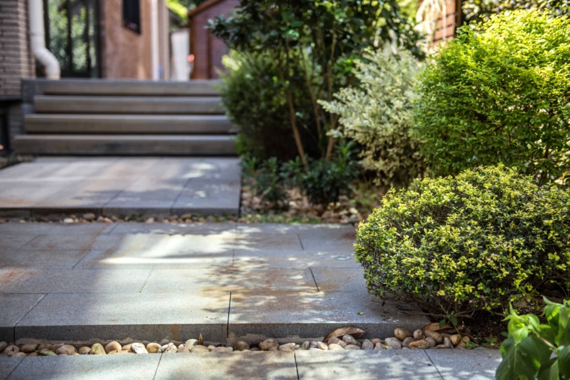 Concrete steps and landscaping with rocks and greenery in a modern outdoor setting.