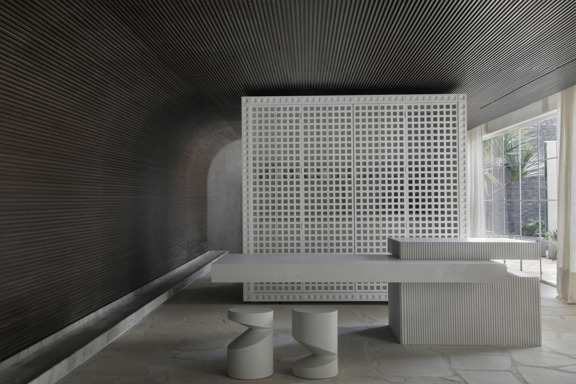 A minimalist concrete interior design featuring a grid wall and contemporary furniture.