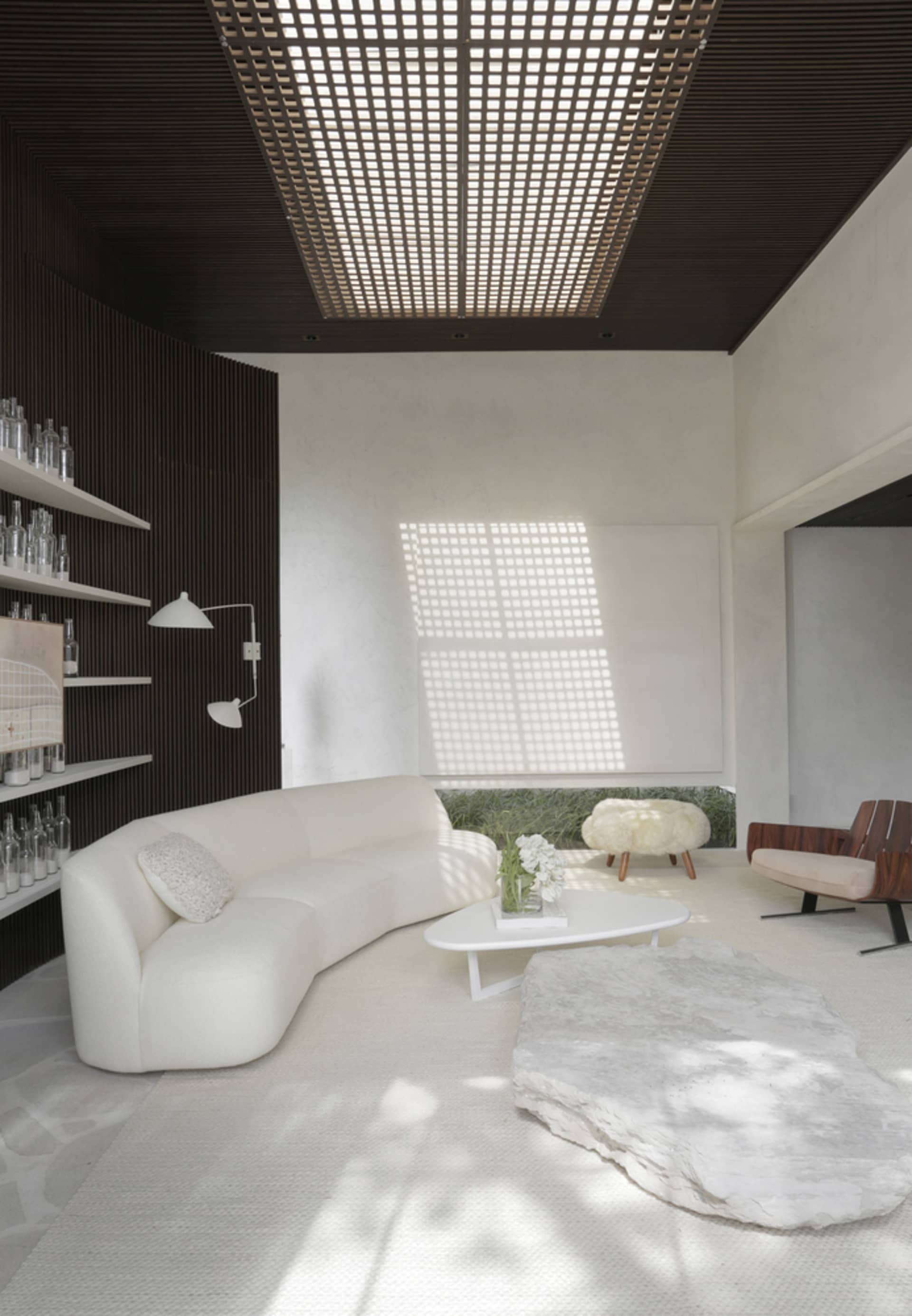 A contemporary living room featuring a sleek, white leather sofa against a minimalist backdrop with a white, textured rug and