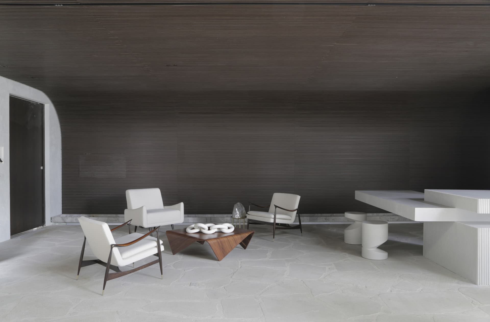 A modern living room with minimalist decor, featuring concrete walls and wooden furniture.