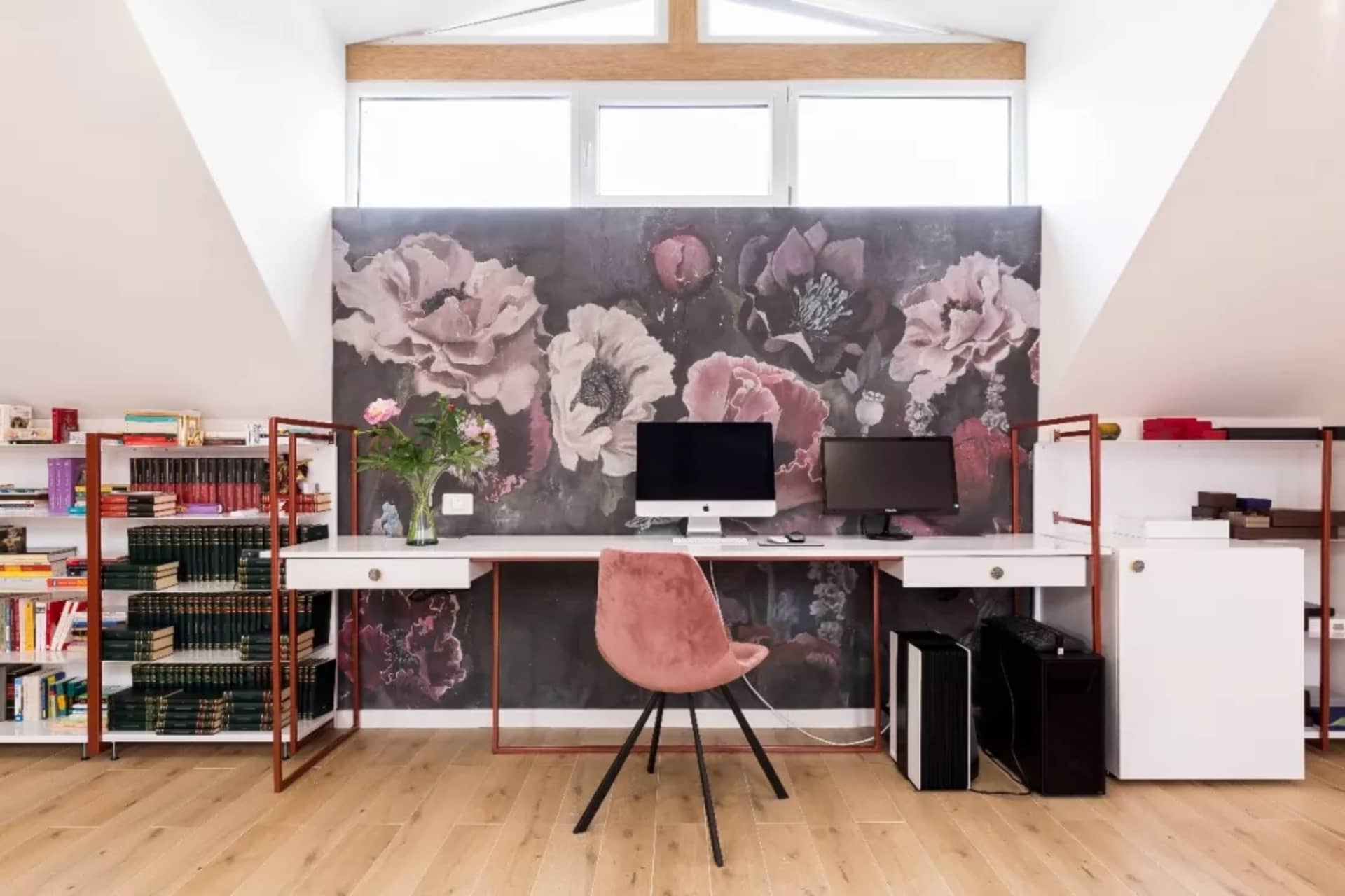 Home office with a modern design featuring a wooden floor and floral wallpaper.