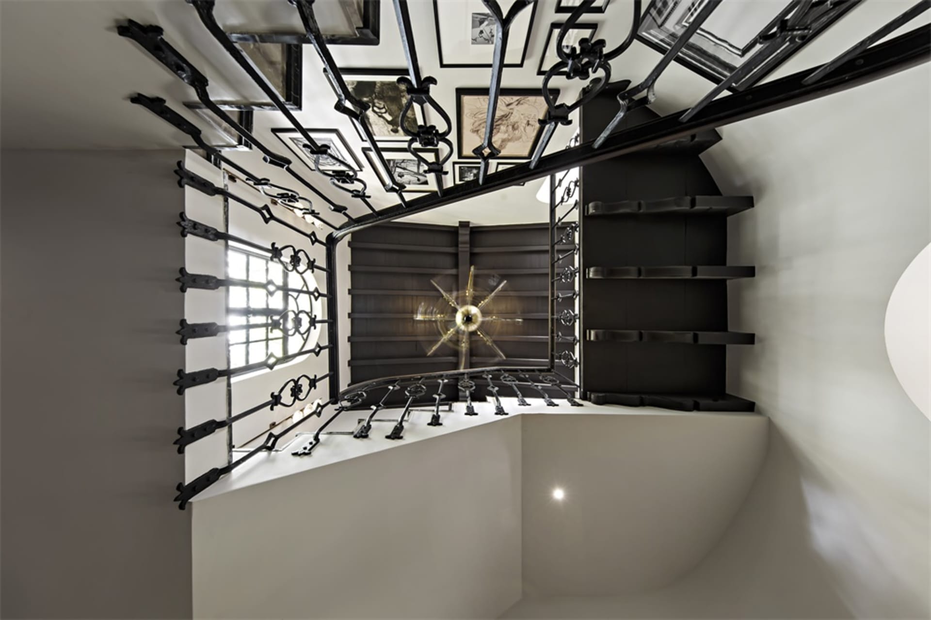 A black metal staircase with intricate railings leading to a white interior space.