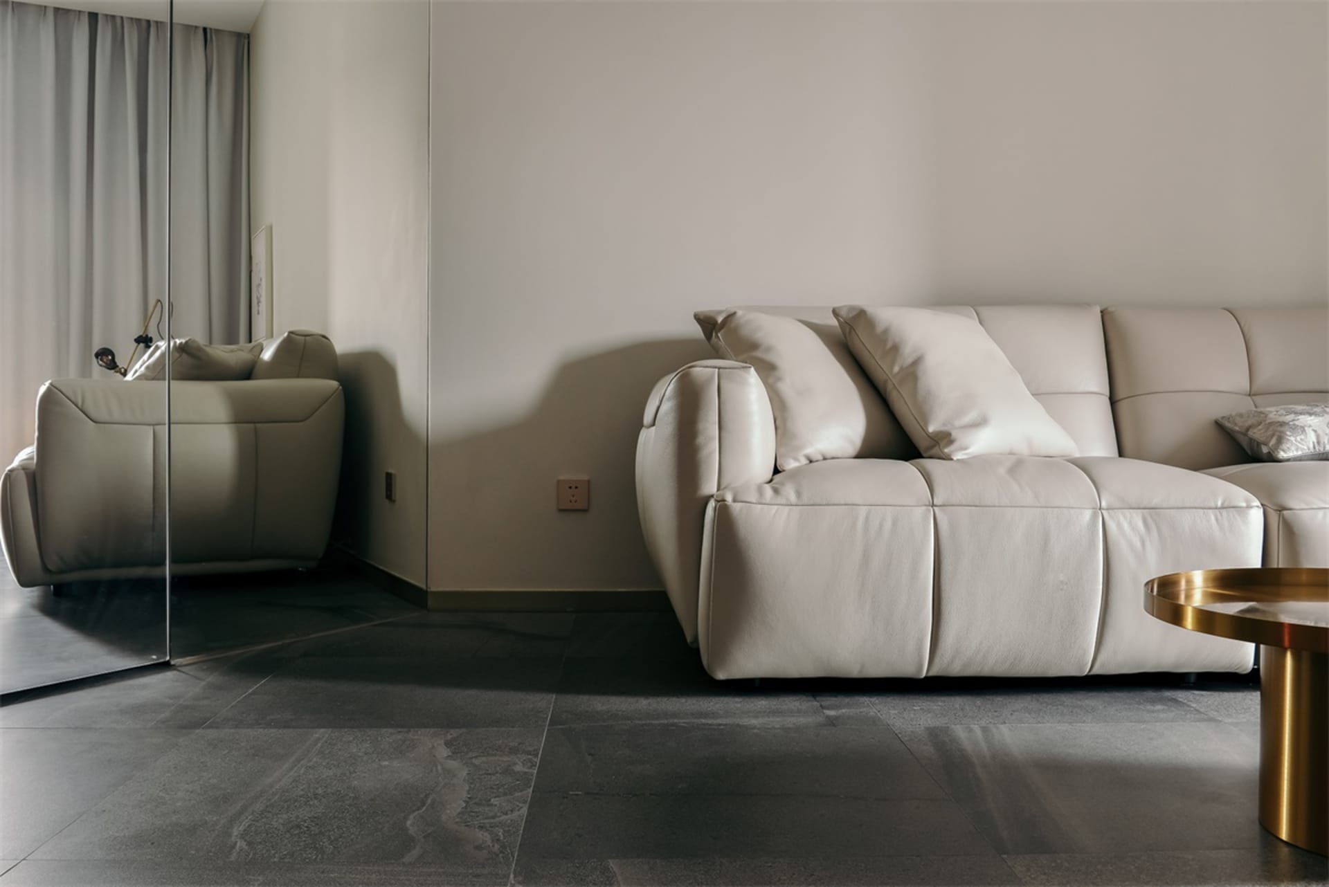 Modern white leather sofa with pillows in a minimalist living room setting.