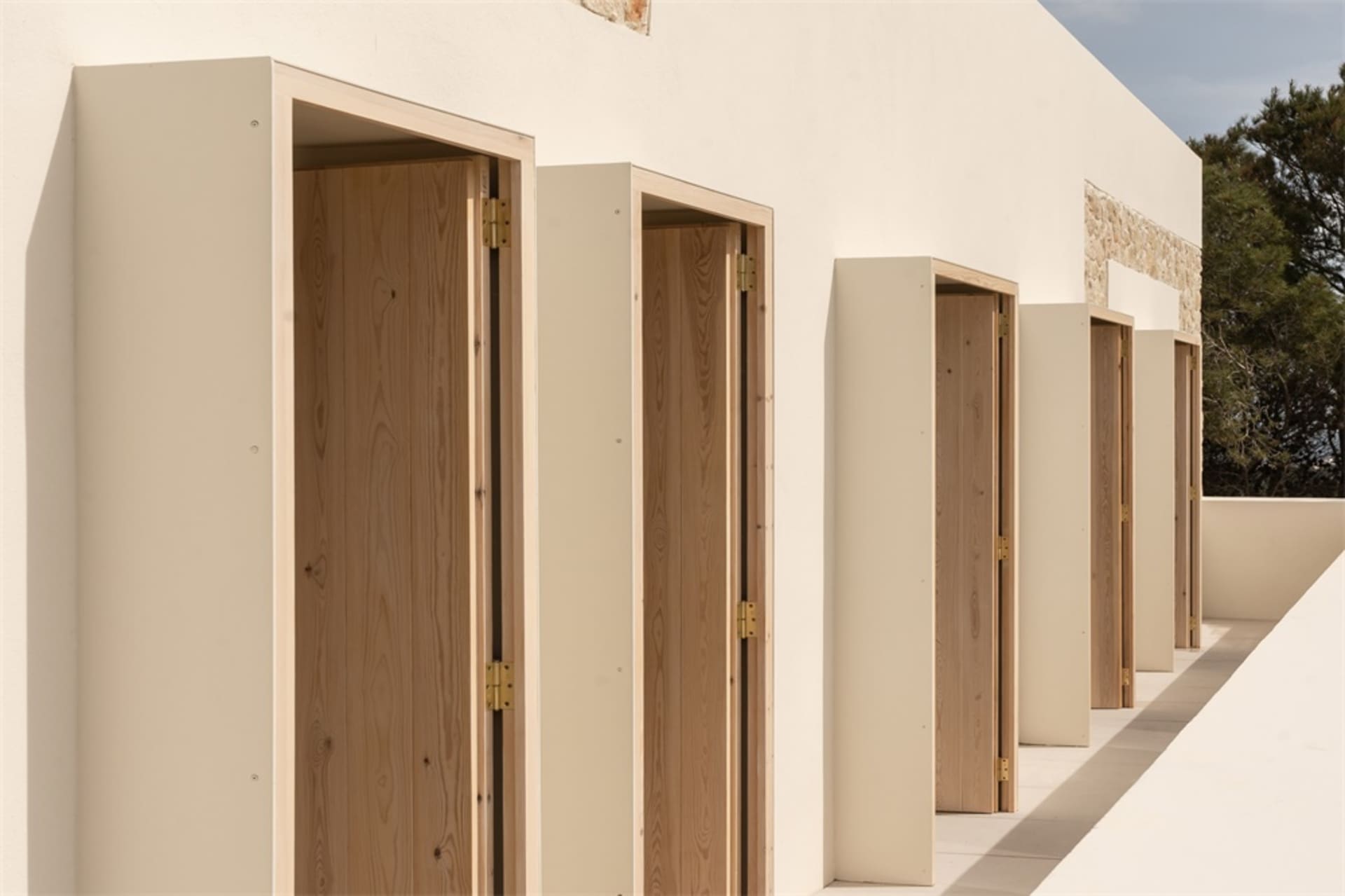 Row of minimalist residential buildings with cream-colored walls and wooden doors.
