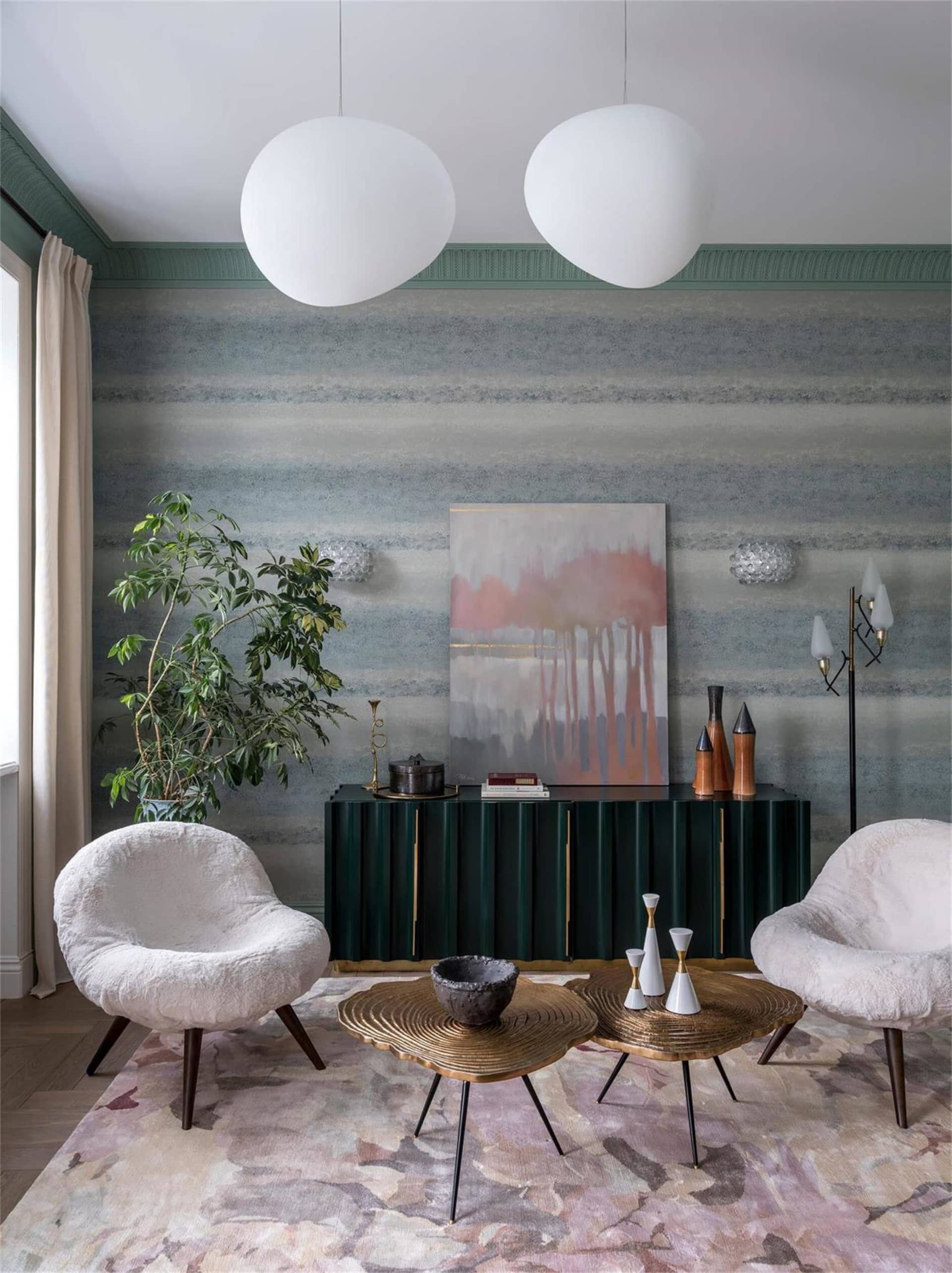 Modern living room with metallic tables, green-wood cabinet, and suede armchairs.