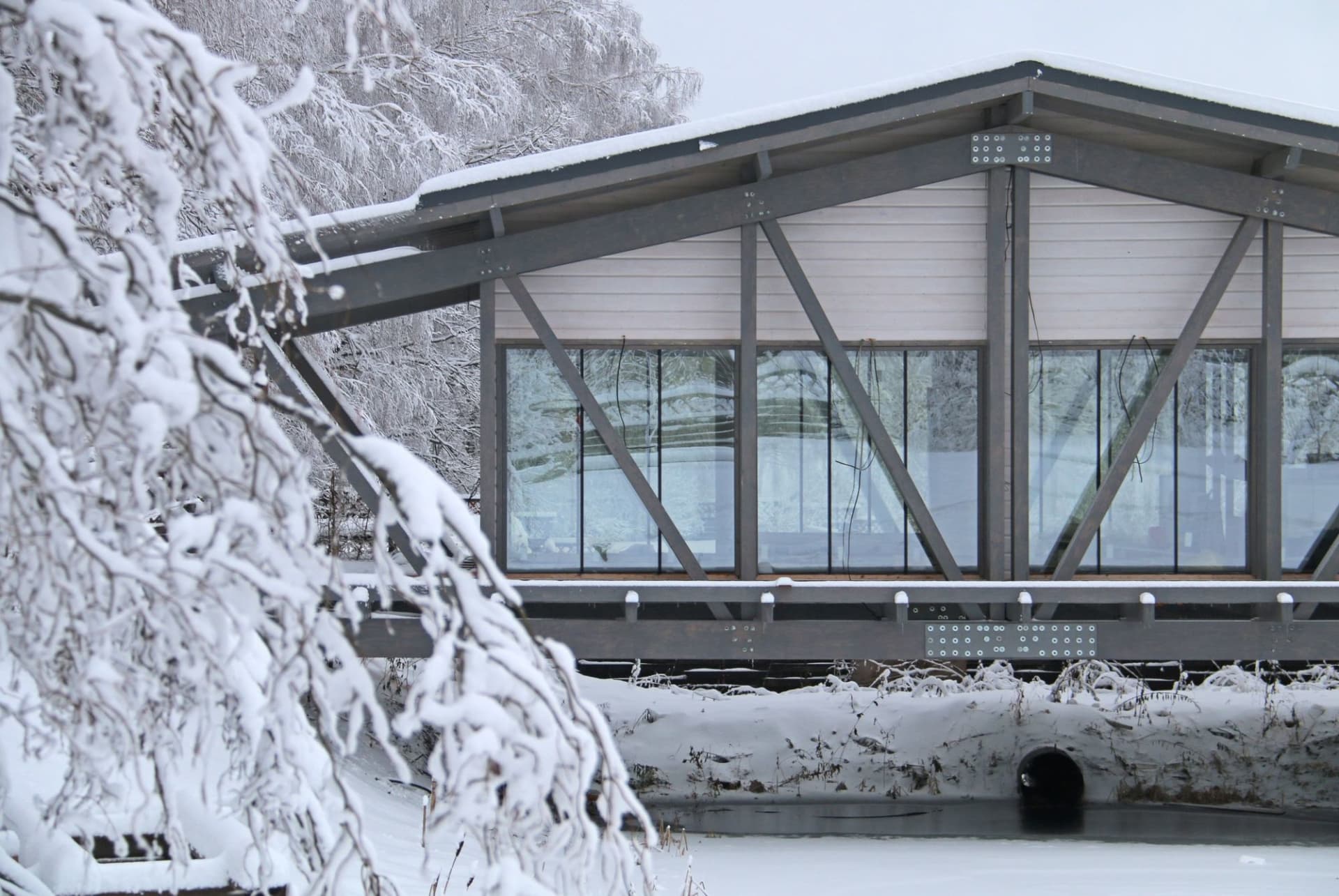 A metallic residential bridge with glass panels over a snowy landscape.