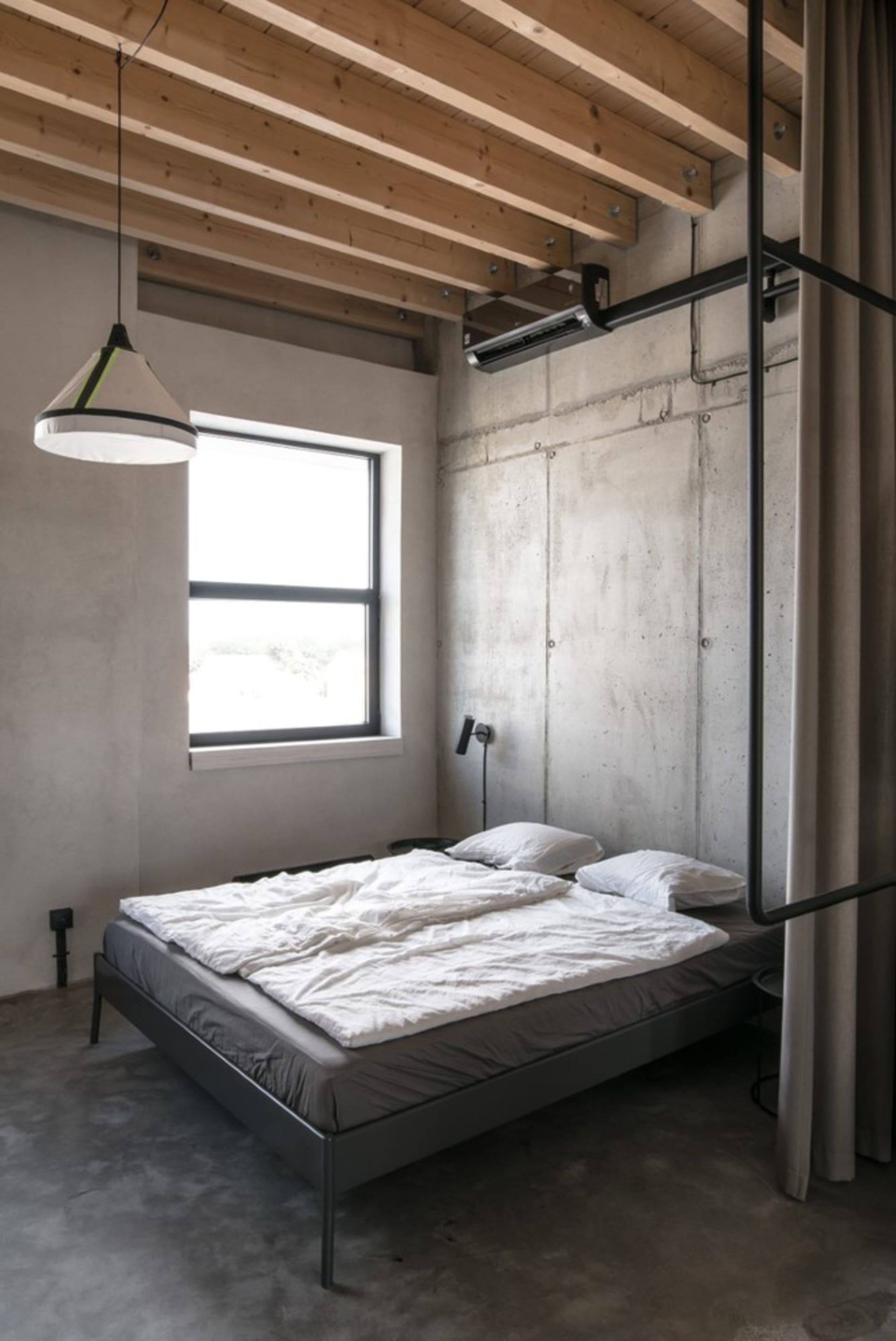 極簡臥室，混凝土地板、白床具，以及天花板上的工業風木樑。