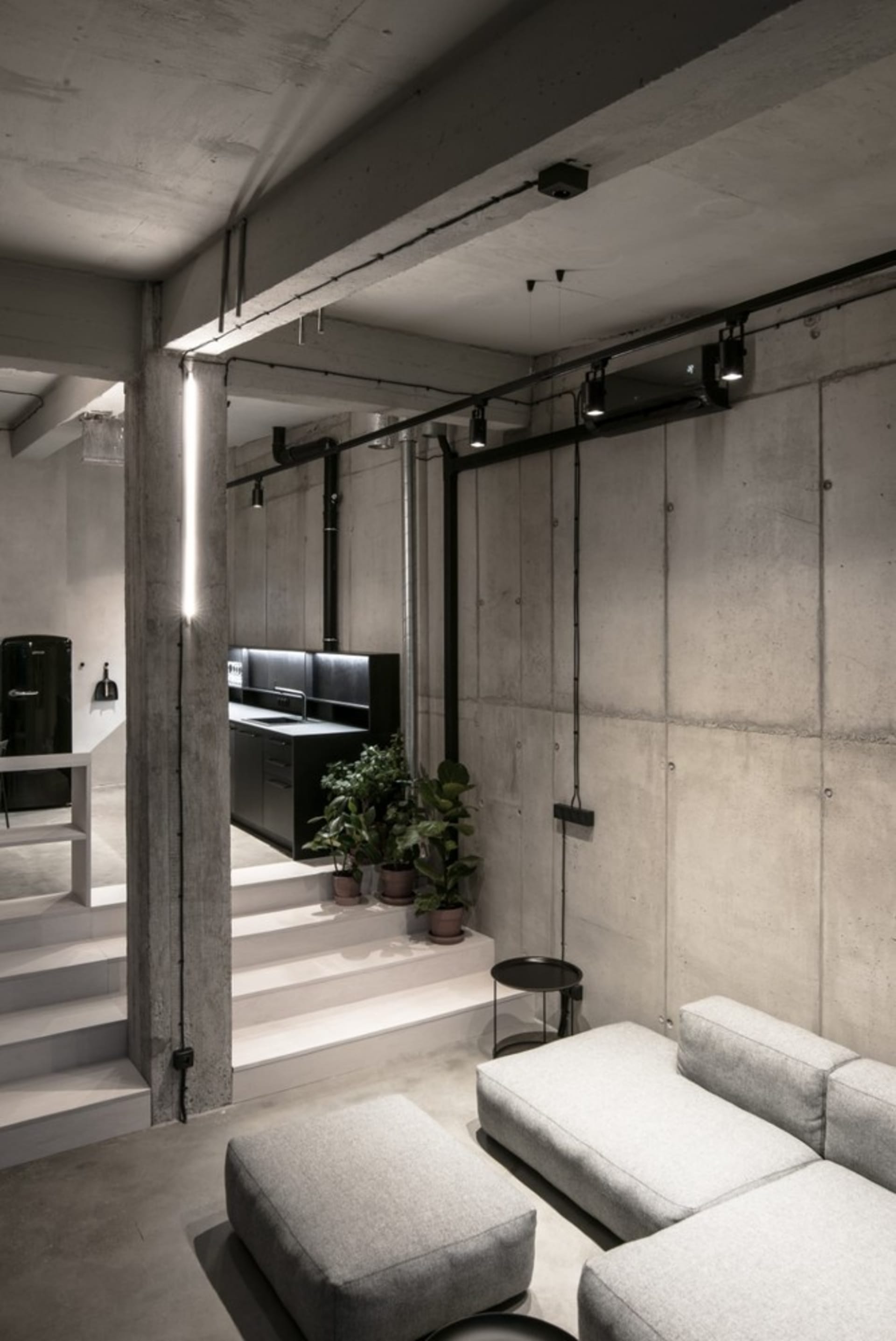 An industrial-style modern living room with concrete walls and black accents.