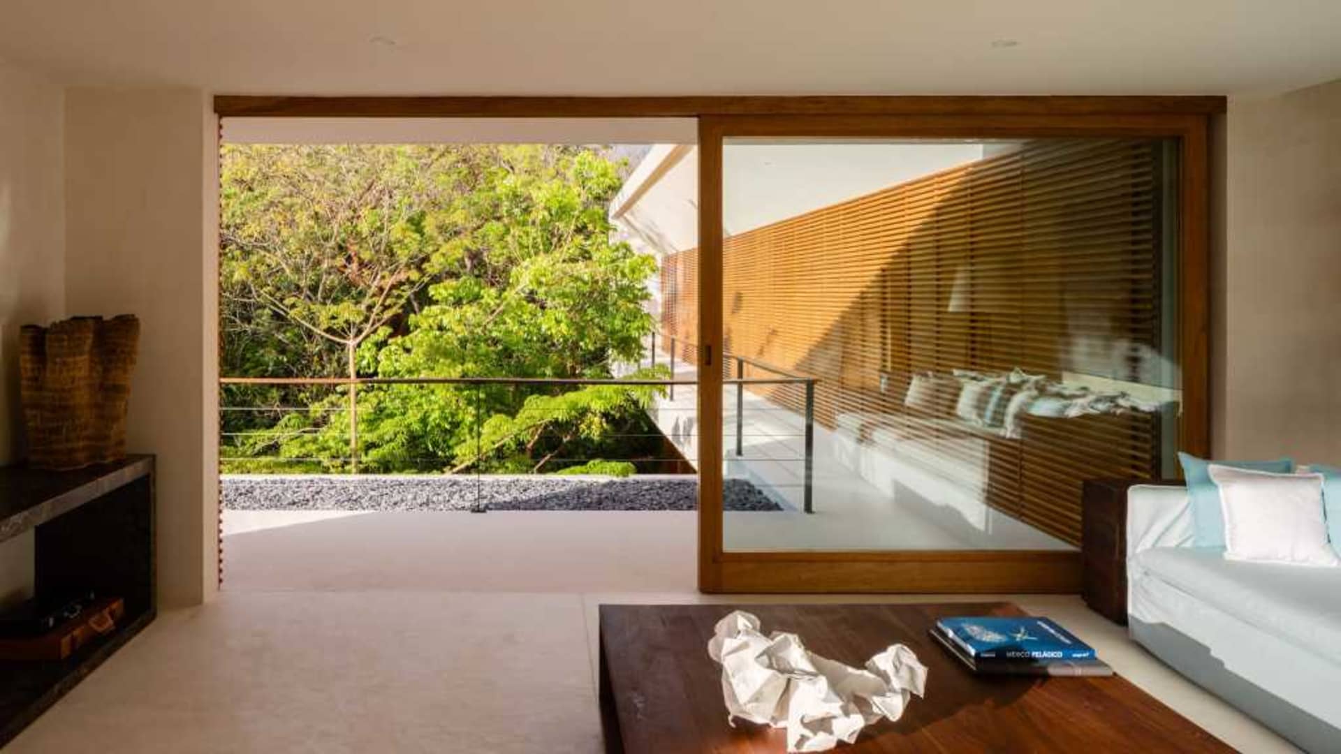 Modern living room featuring wooden blinds, glass balustrade, and concrete floor.