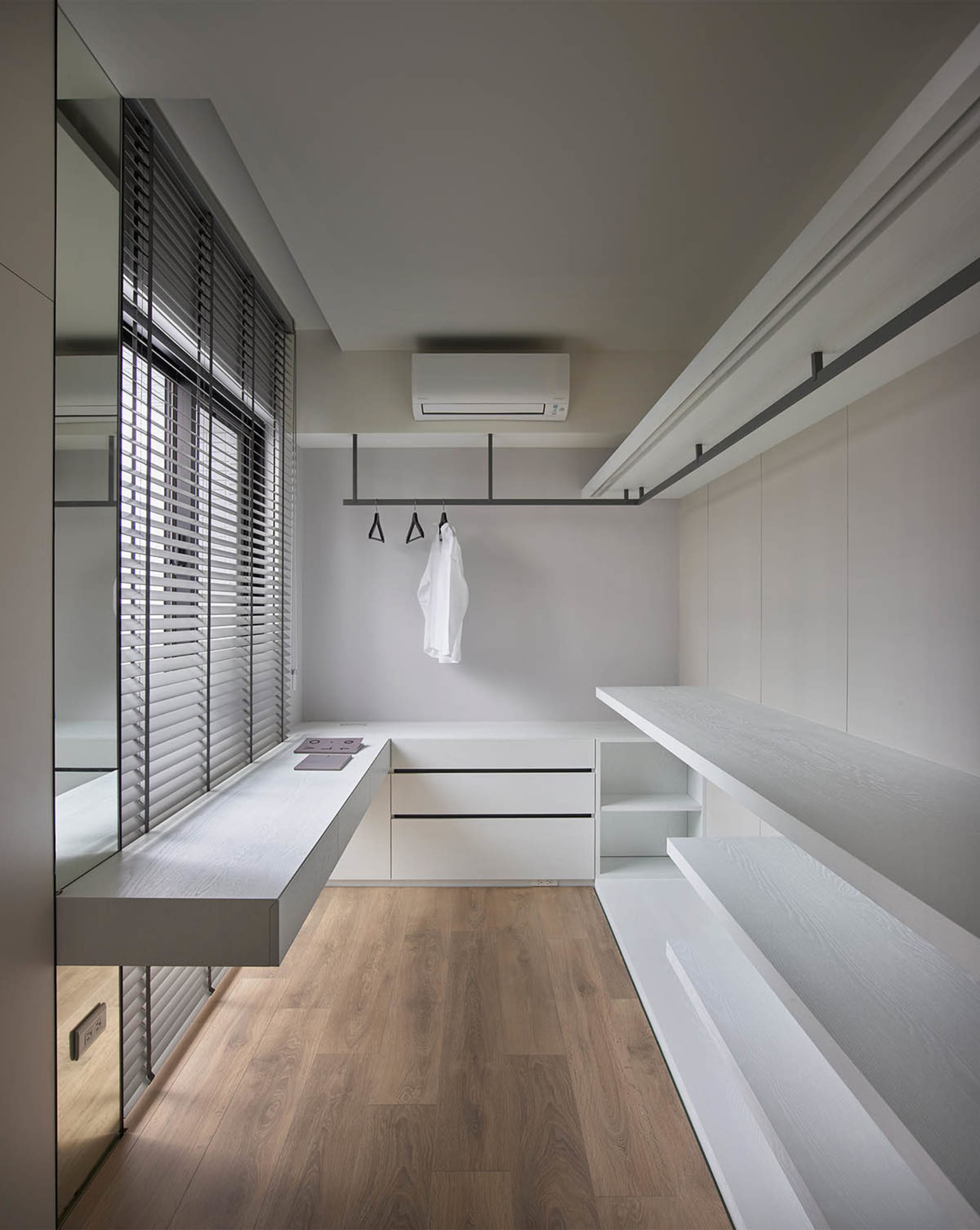 Modern white closet with minimalist design and wooden flooring.