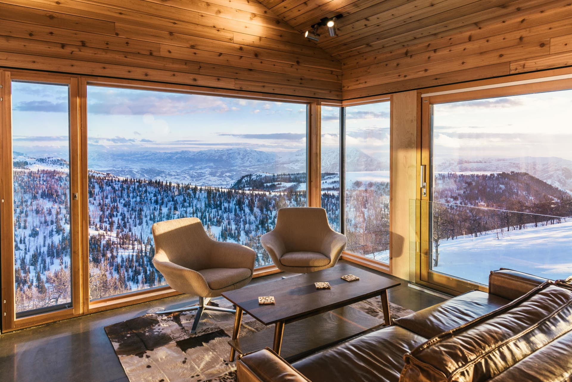 Modern interior design living room with wooden walls, floor-to-ceiling windows showcasing a snowy mountain view, comfortable 