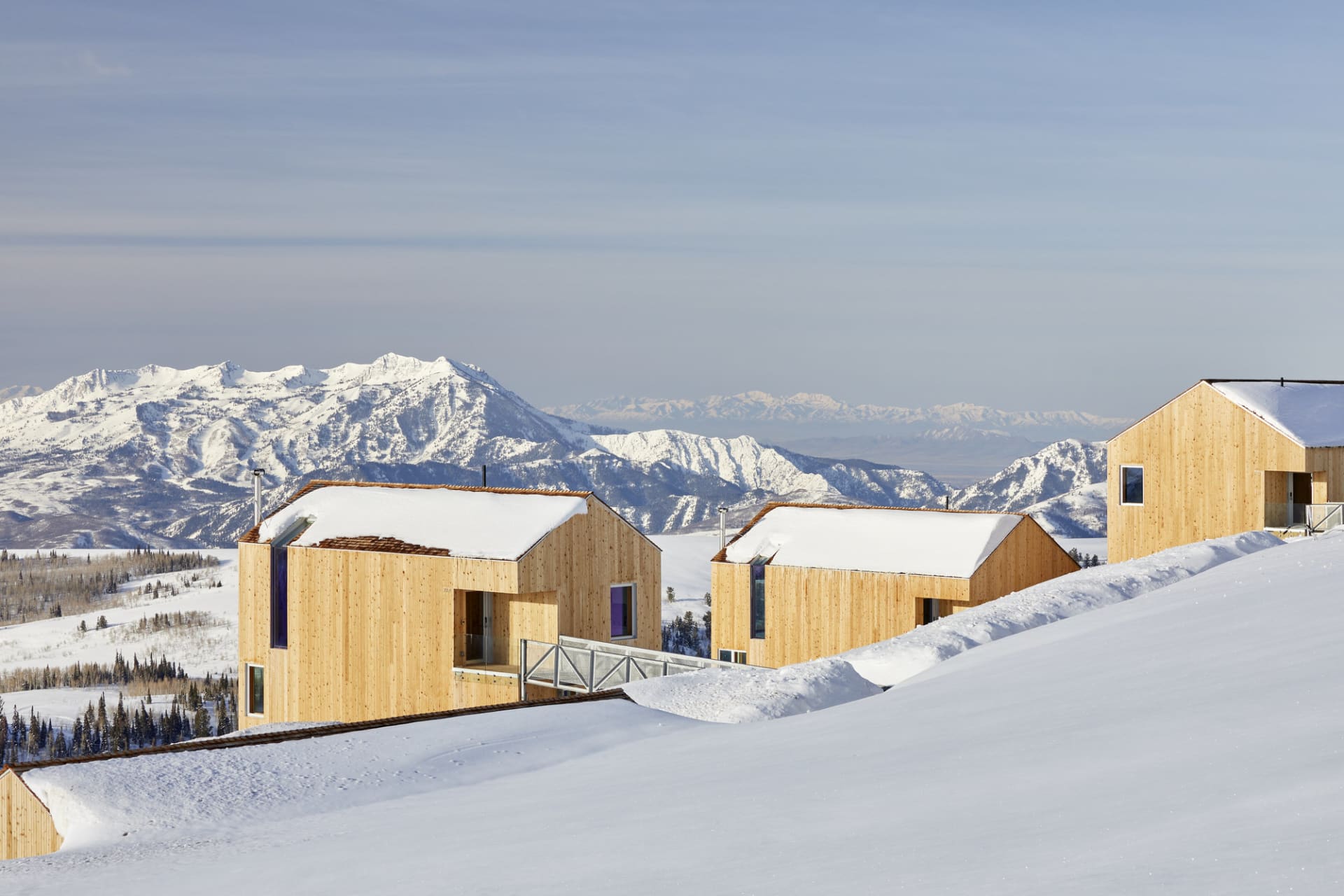 現代極簡住宅覆蓋在雪中，背景為山巒。