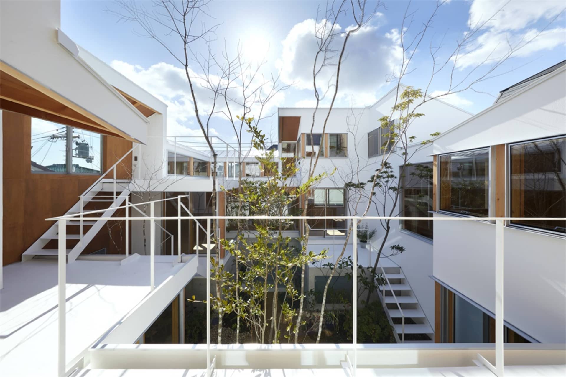 一棟白色灰泥外牆的住宅,庭院內有樹木與現代設計元素。