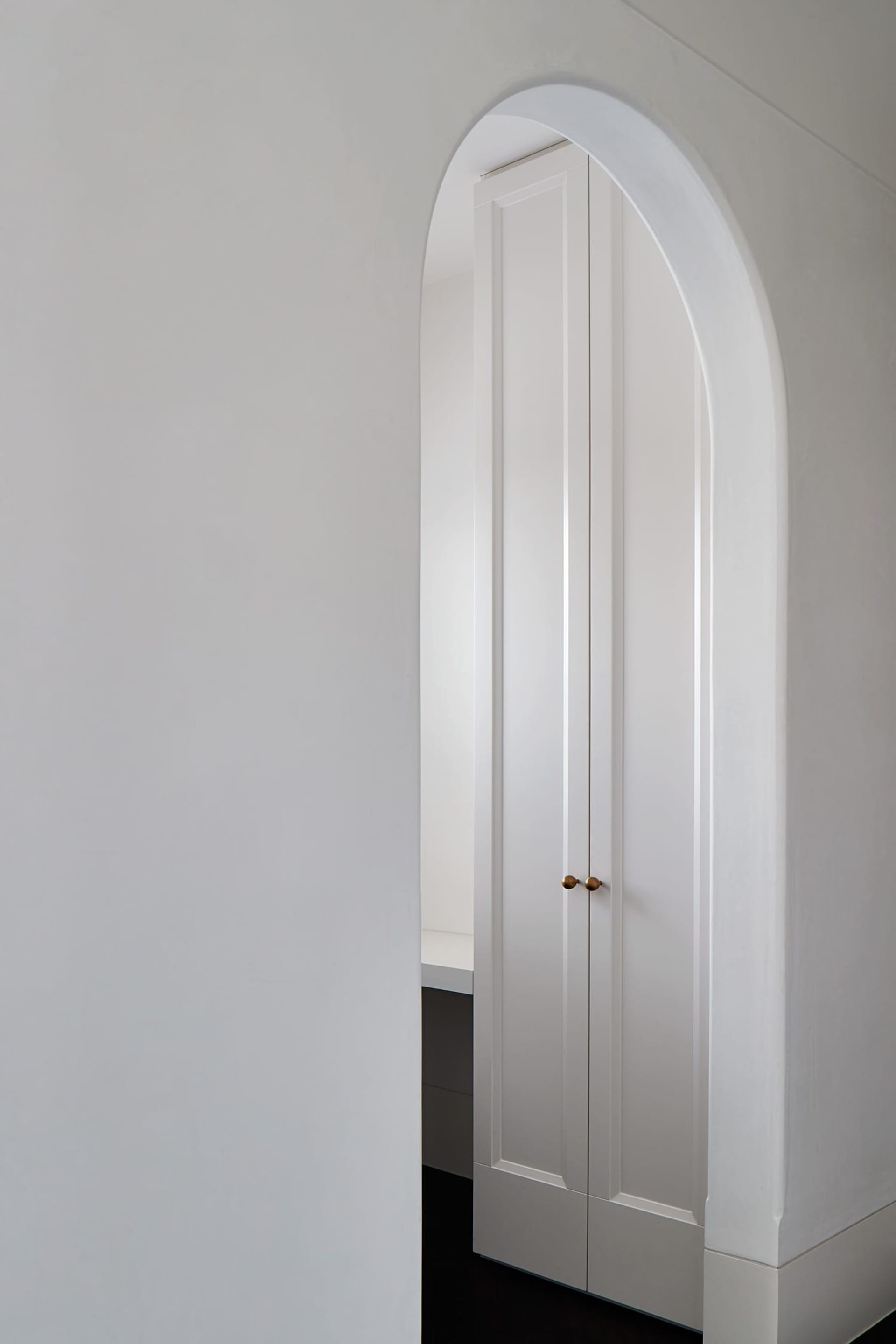 A modern white doorway interior with curved archway and minimalist design.