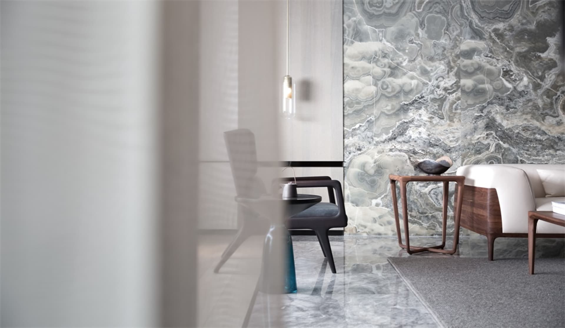 A modern living room featuring marble walls and furniture.