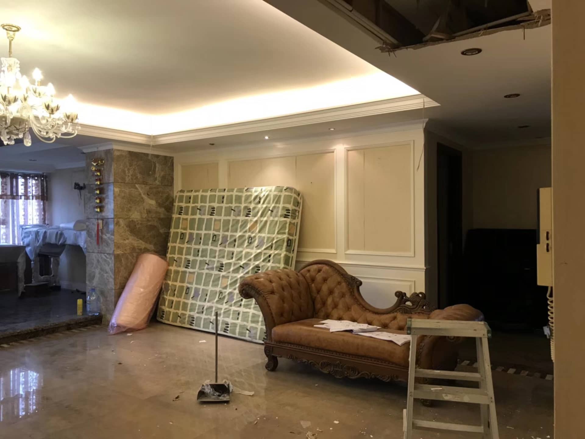 客廳內有混凝土地板、大理石柱,以及翻修工具。