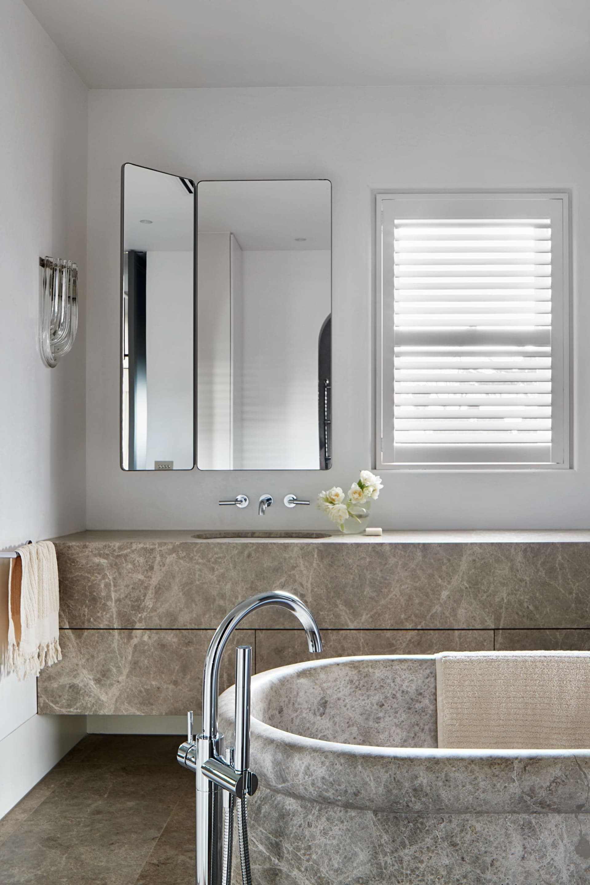 Modern bathroom with a freestanding marble bathtub, sink, and a mirror above the sink area.