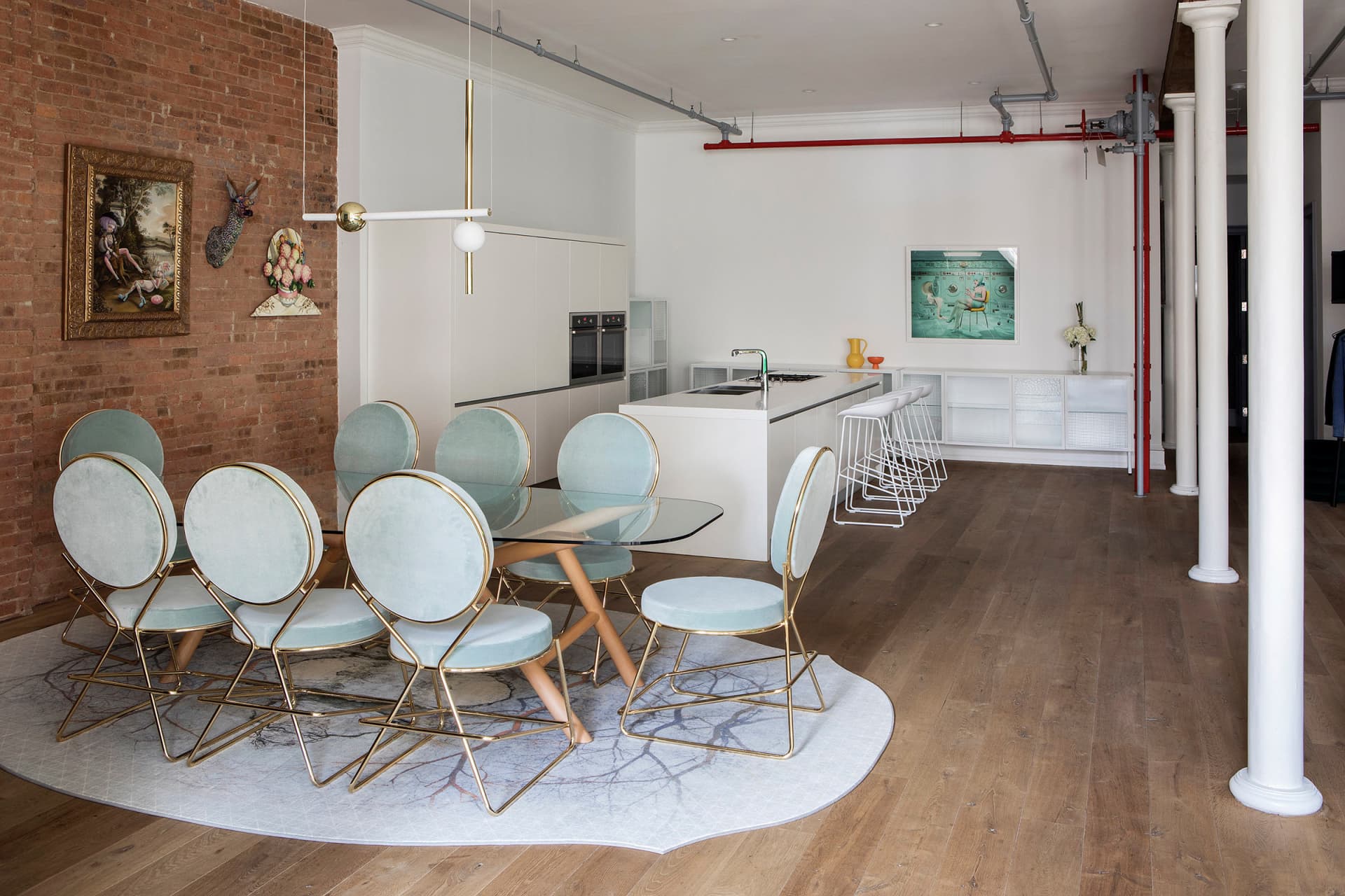 Modern residential space featuring a dining table with blue upholstered chairs and metal framing, a kitchen island, and a bri