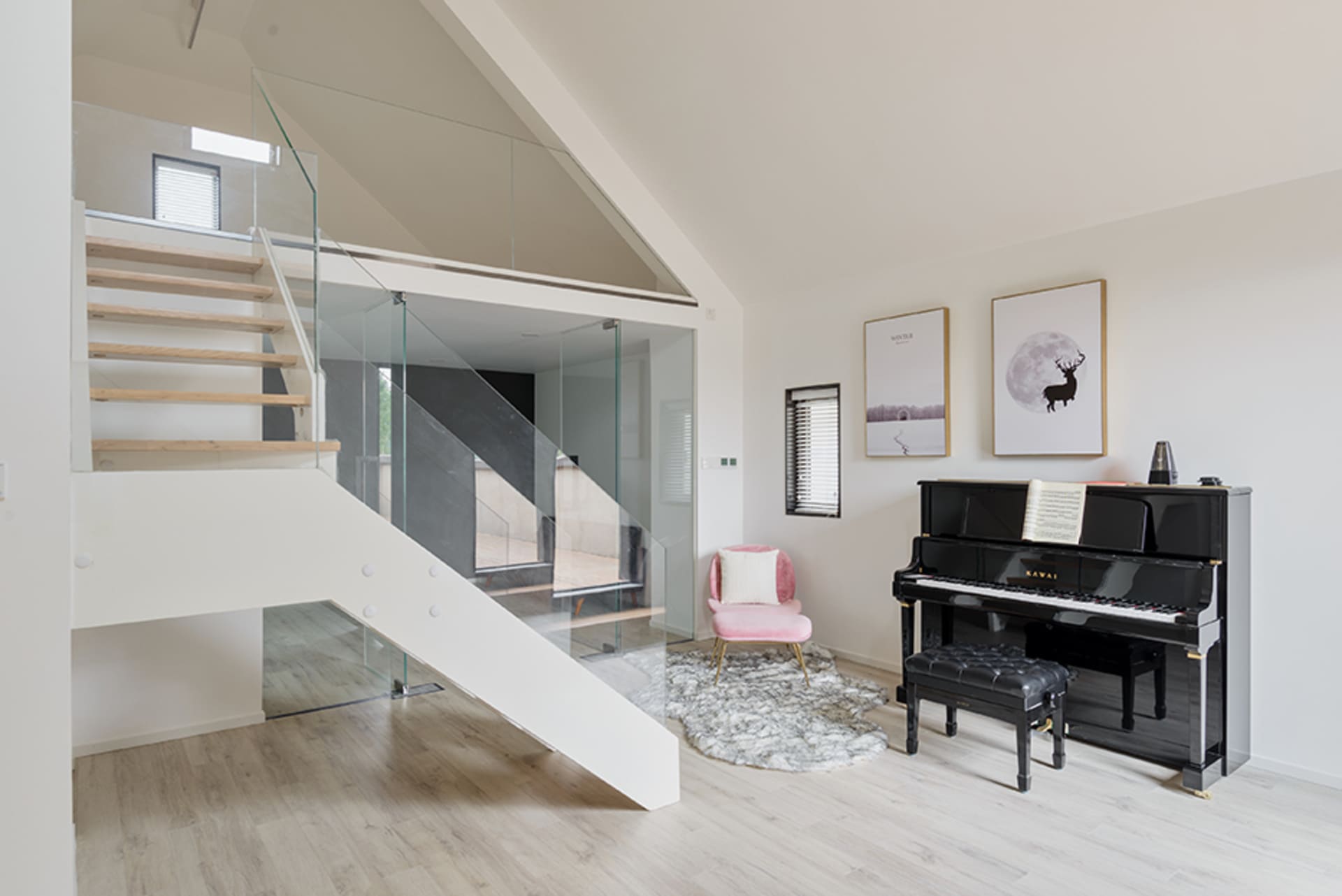 A modern music room featuring a black upright piano on a white wooden floor, with a pink armchair and a deer-themed poster on