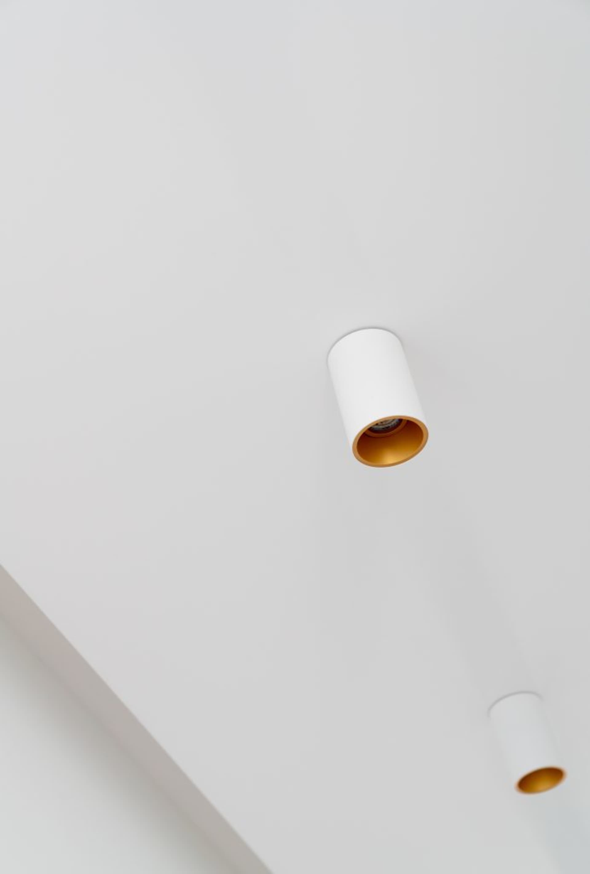 A minimalist lighting fixture mounted on a white ceiling.