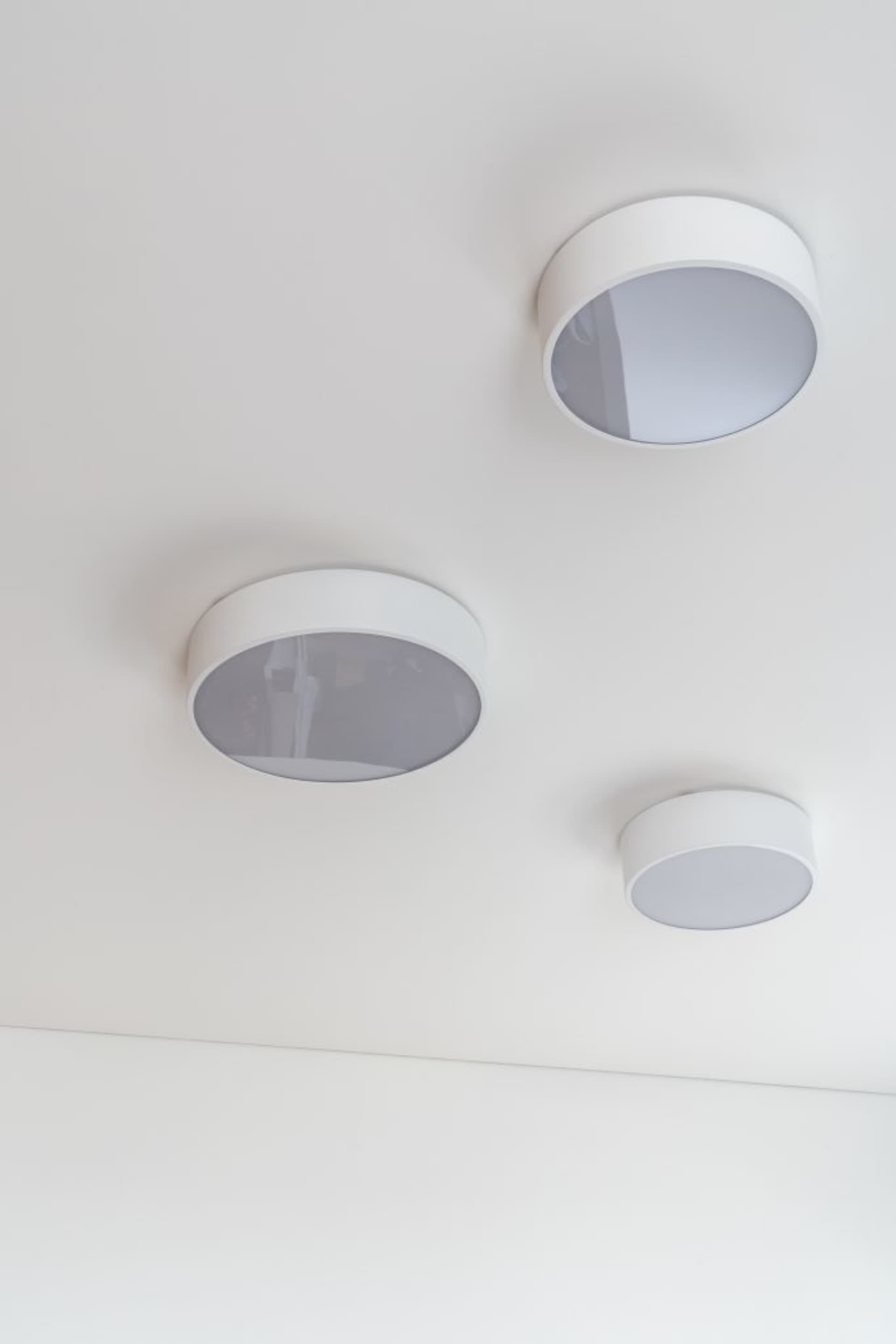 Three round ceiling lights with black and white designs in a modern interior setting.