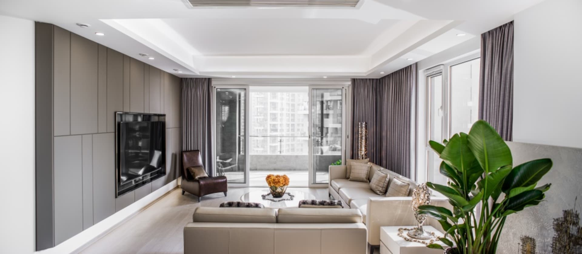 A modern living room featuring neutral-toned upholstery, large windows, and a sleek design aesthetic.