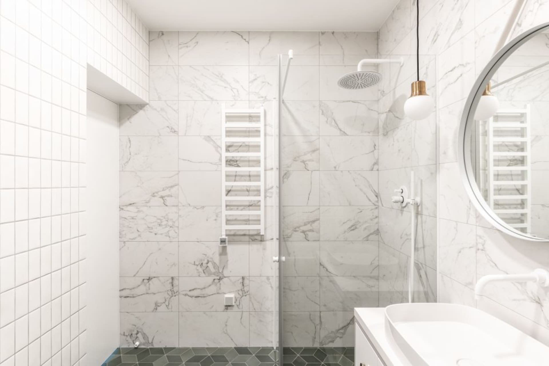 A modern bathroom with marble tiles and a glass shower enclosure.