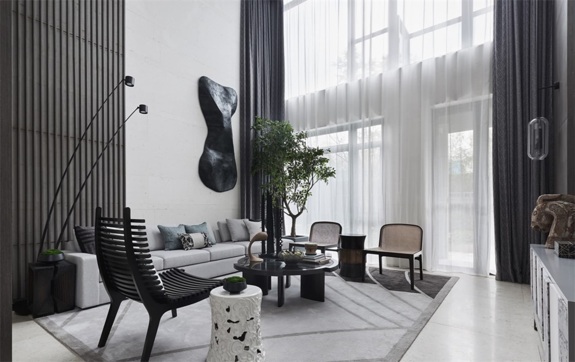 Modern, minimalist living room featuring black furniture, a large sofa, and large windows with sheer curtains, set against a 