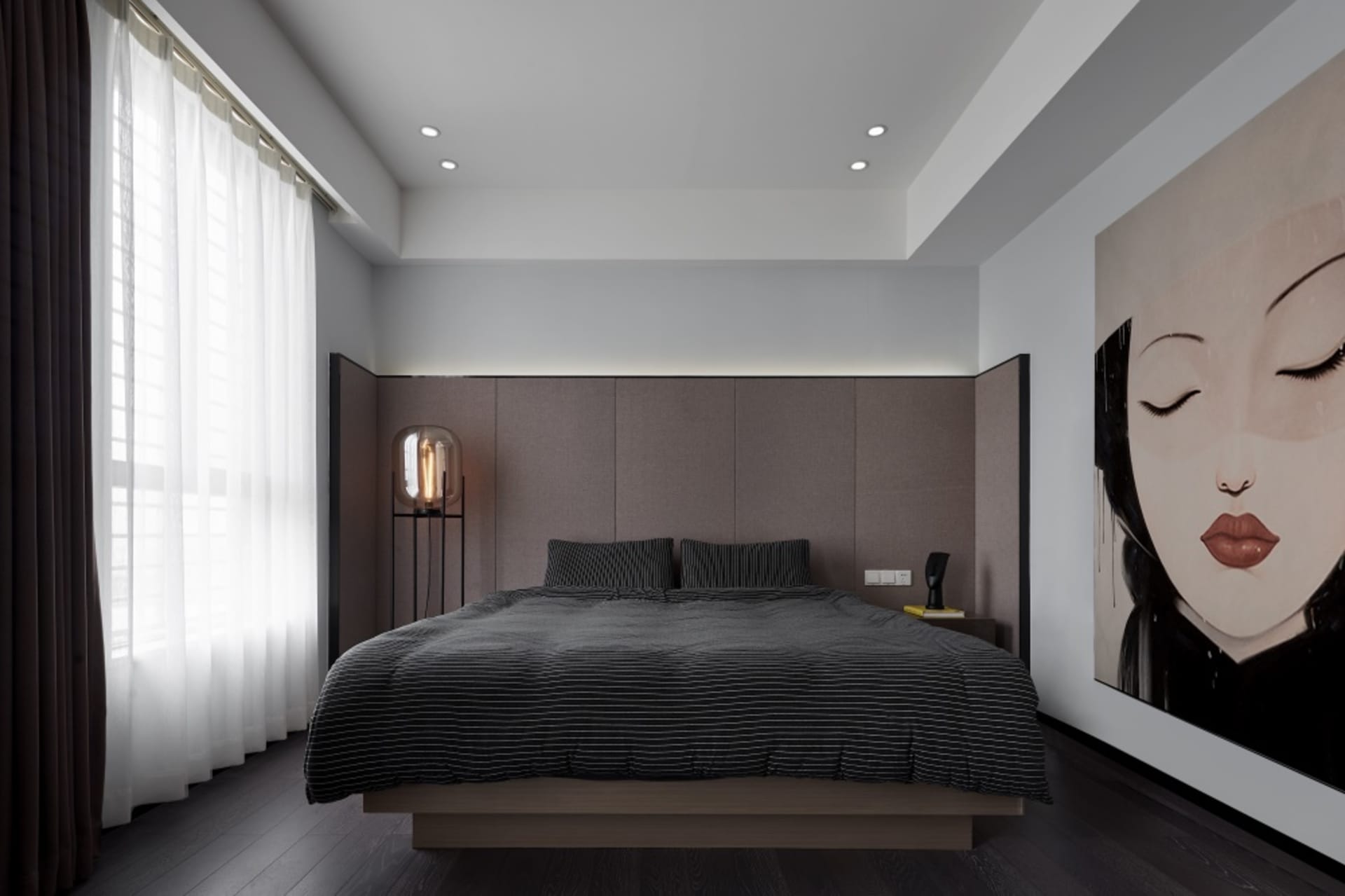 A modern bedroom featuring a wooden platform bed and a large, framed portrait of a woman's face.