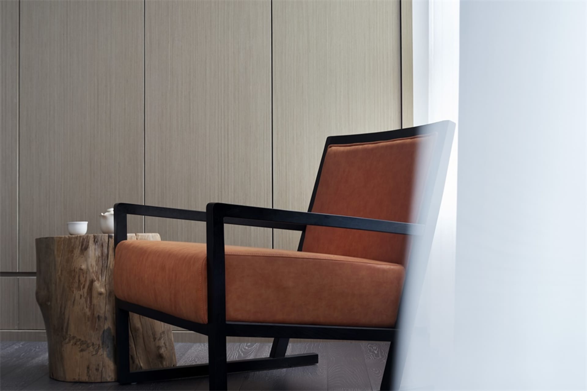 A modern wooden armchair with an orange cushion in a living room setting.