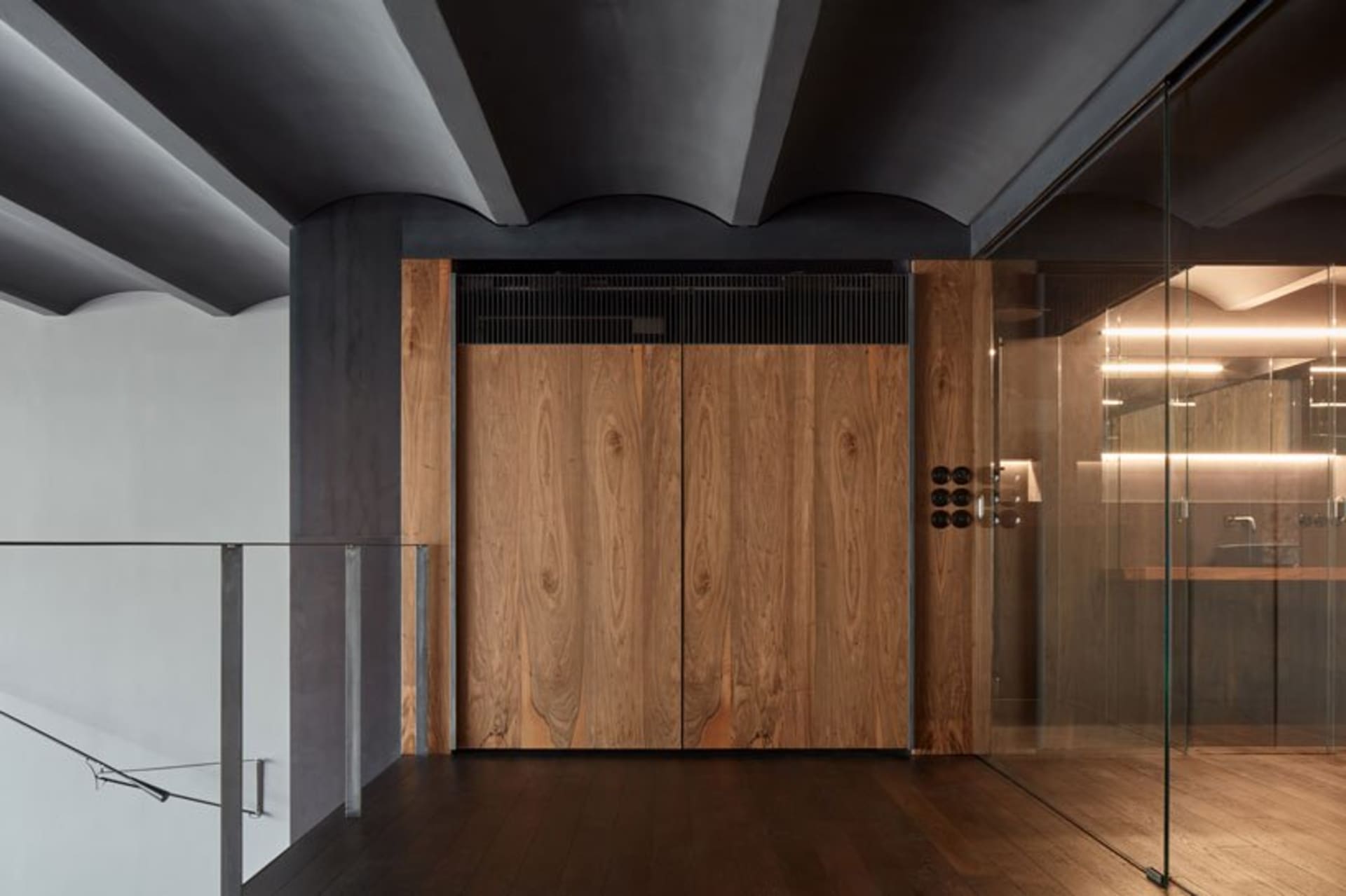 Modern residential entryway featuring wooden doors, metallic accents, and glass panels.